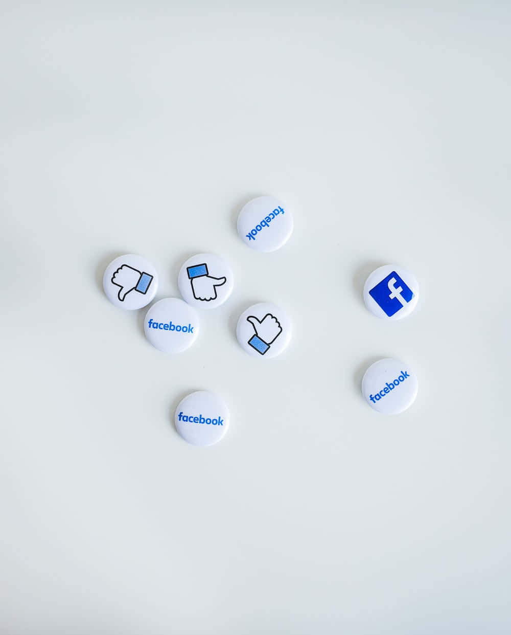 Application 桌布 壁紙 — 白色圓形Facebook主題按鈕，帶有豎起拇指和拇指向下及標誌，散落在純淺灰色表面上。