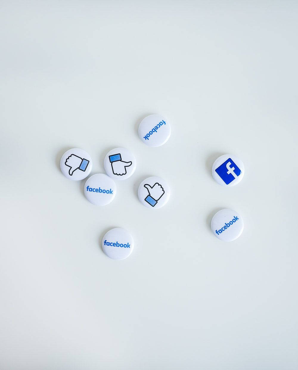 Social 桌布 壁紙 — 白色圓形Facebook品牌按鈕，帶有豎起大拇指和放下大拇指圖示，散落在純淺灰色表面上。