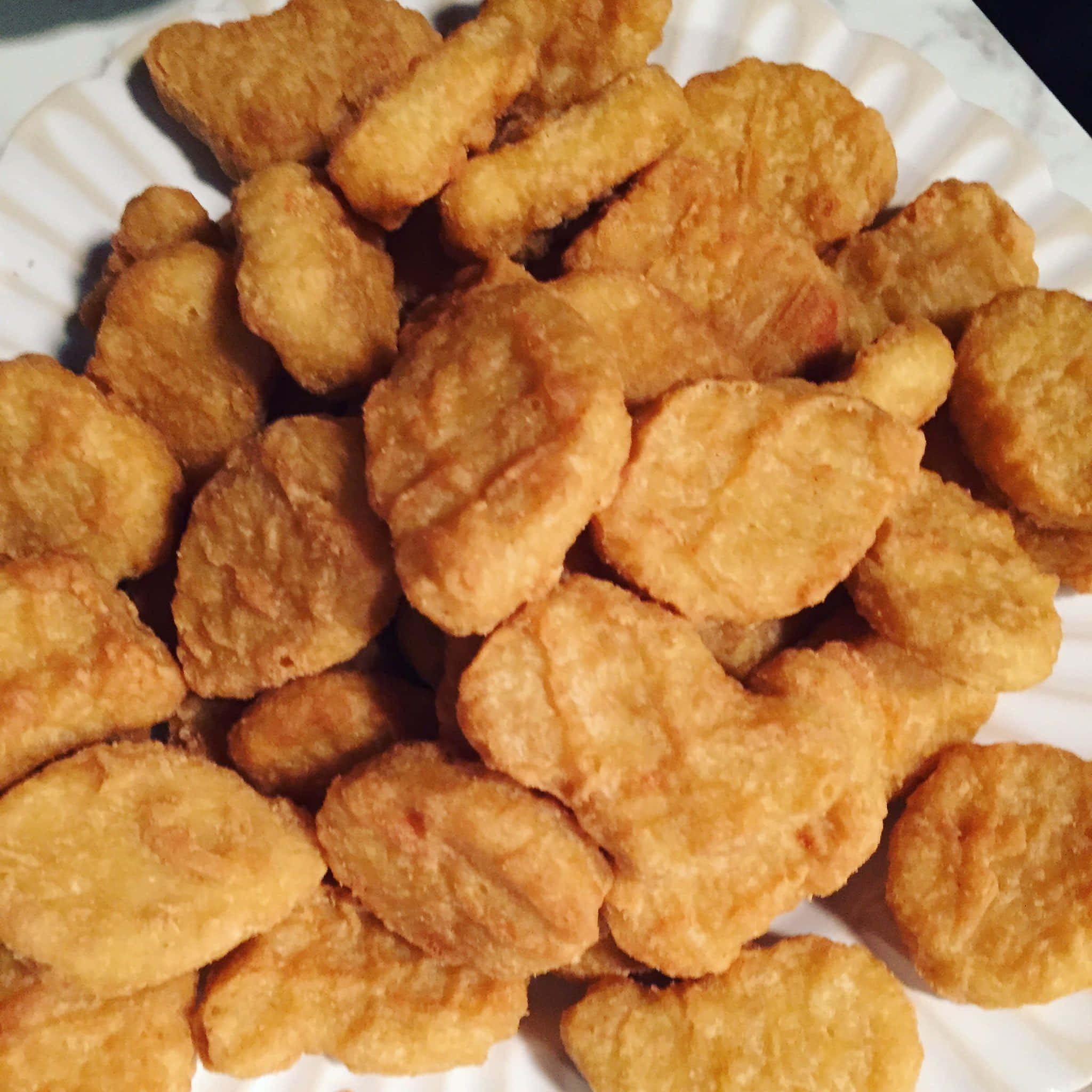 Chicken Nuggets 桌布 壁紙 — 白色坑紋紙盤上堆滿金黃色炸雞塊的特寫。