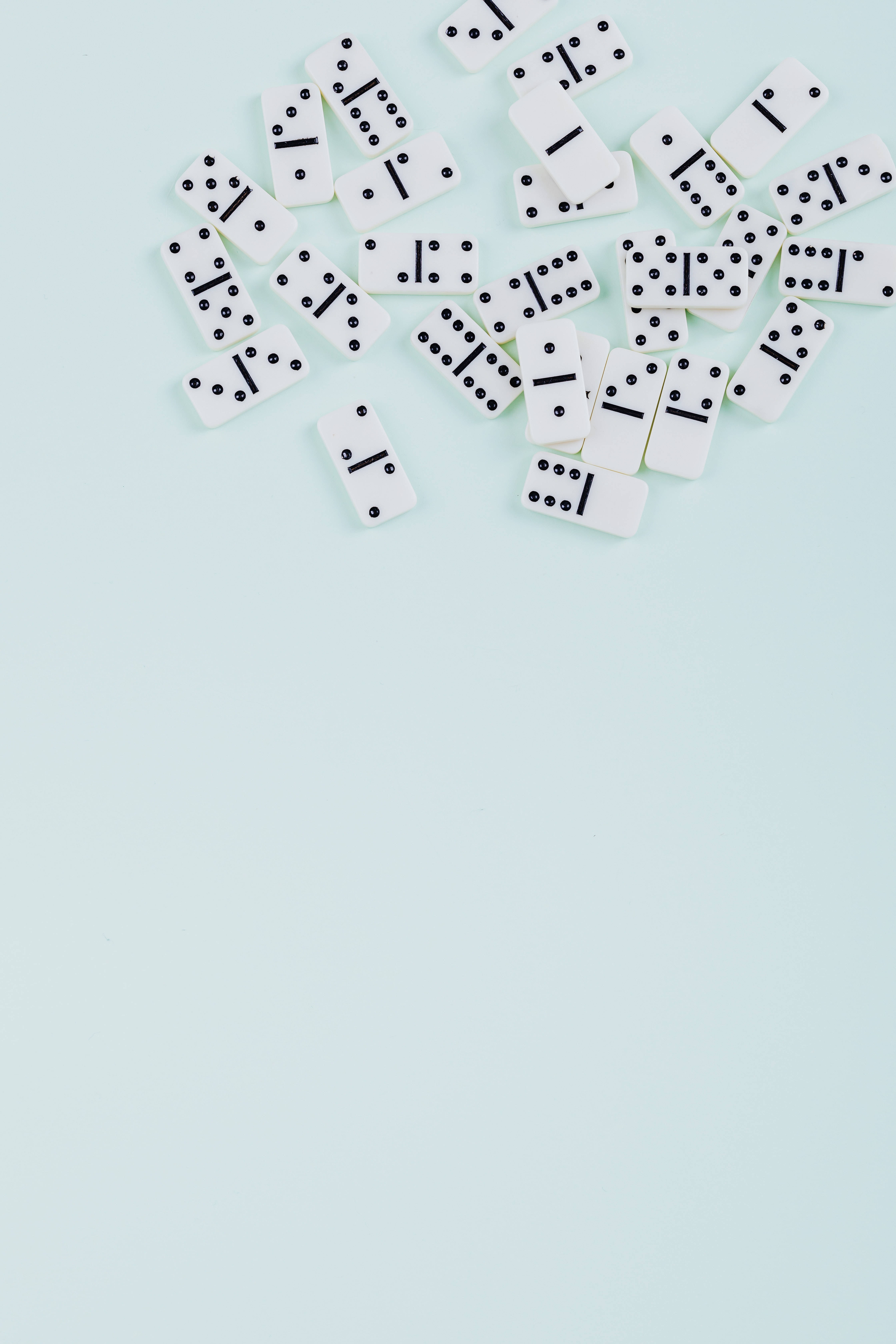 dominos 桌布 壁紙 — 白色多米諾骨牌隨意散落在柔和的薄荷綠色背景上，留有充足的負空間。