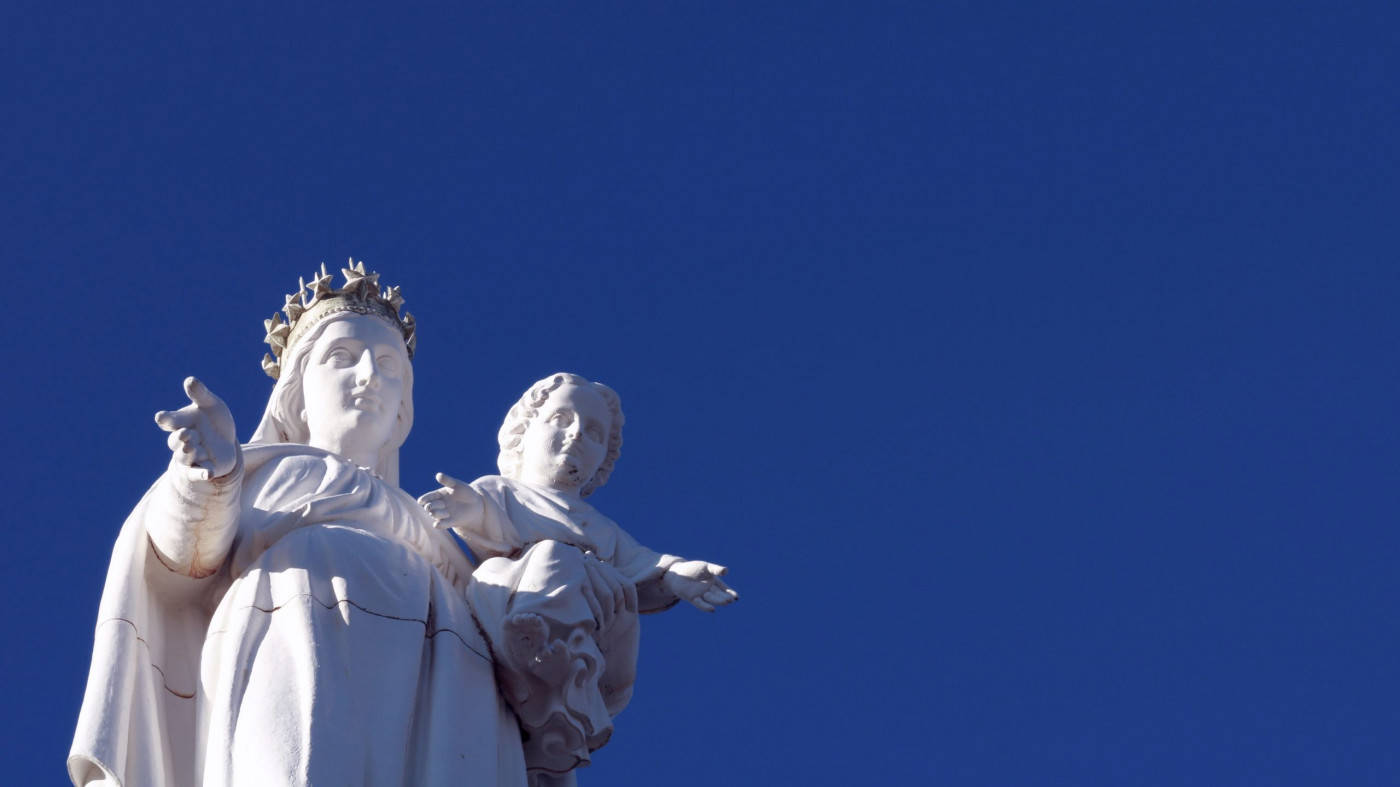Virgin Mary 桌布 壁紙 — 白色大理石聖母瑪利亞懷抱基督聖嬰雕像，襯托著鮮豔的藍天。