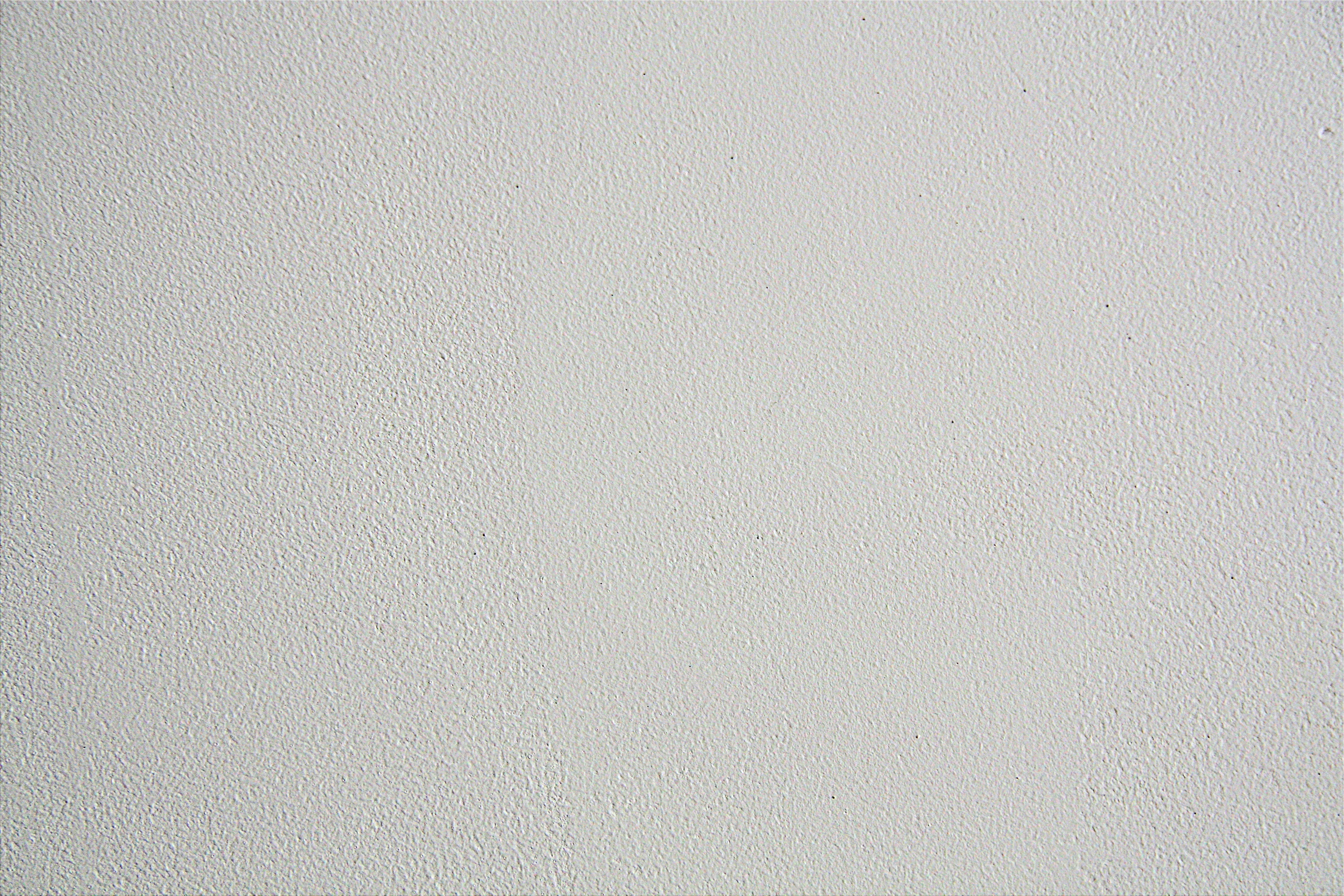 Concrete Texture 桌布 壁紙 — 白色平滑紋理牆面特寫，帶有細微顆粒和小斑點。