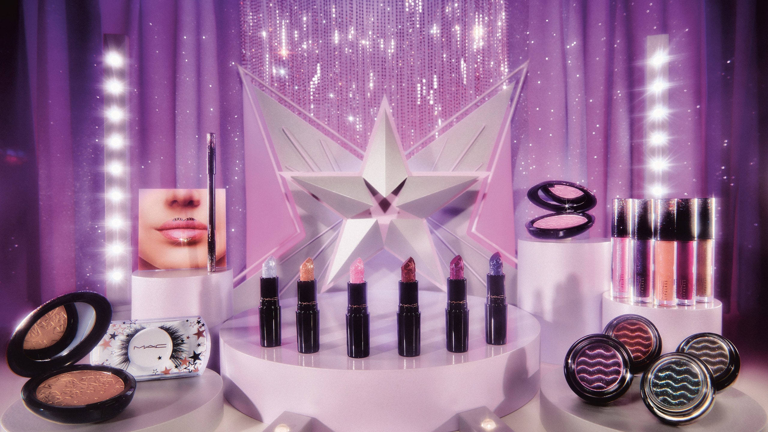 Cosmetics 桌布 壁紙 — 白色底座上陳列的MAC化妝品華麗展示，背景為閃爍紫色及星形裝飾。