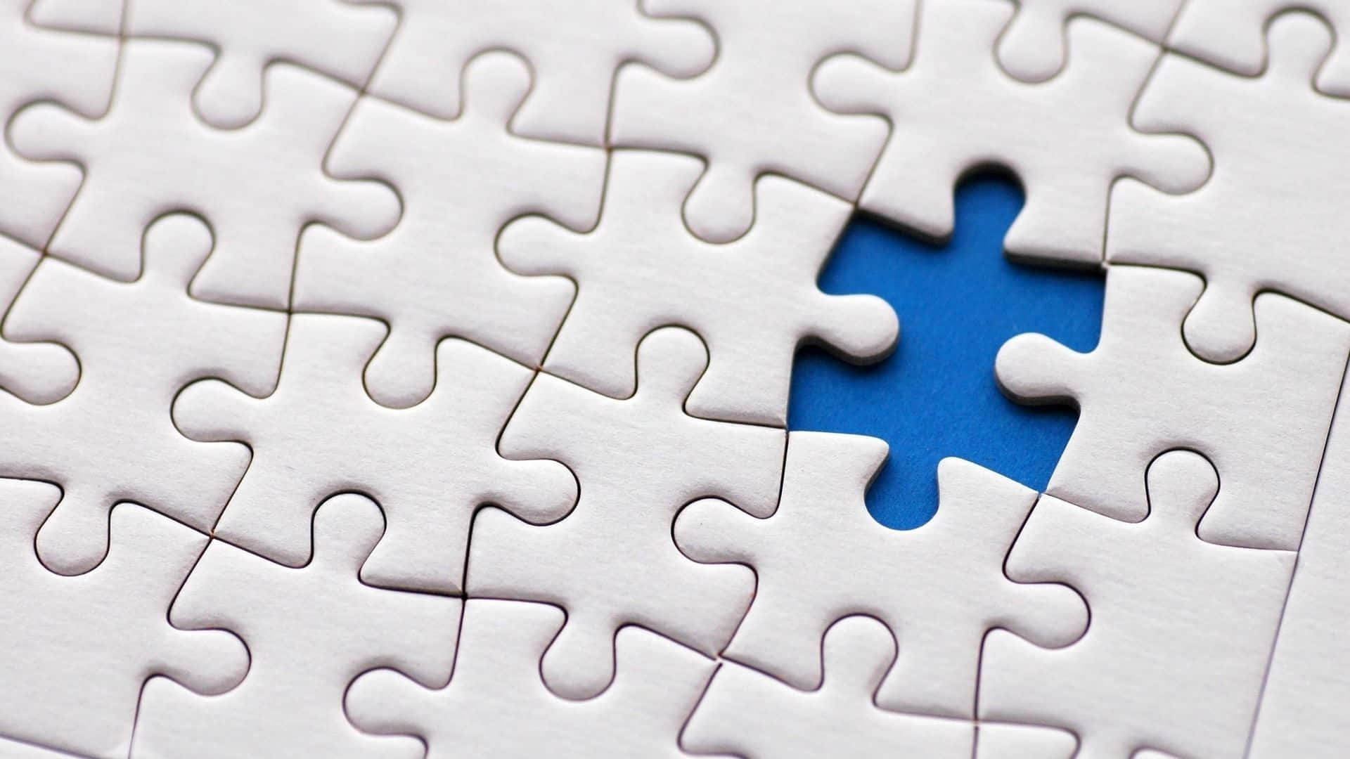 Puzzle 桌布 壁紙 — 白色拼圖塊的特寫，其中一塊缺失，露出充滿活力的藍色空隙。