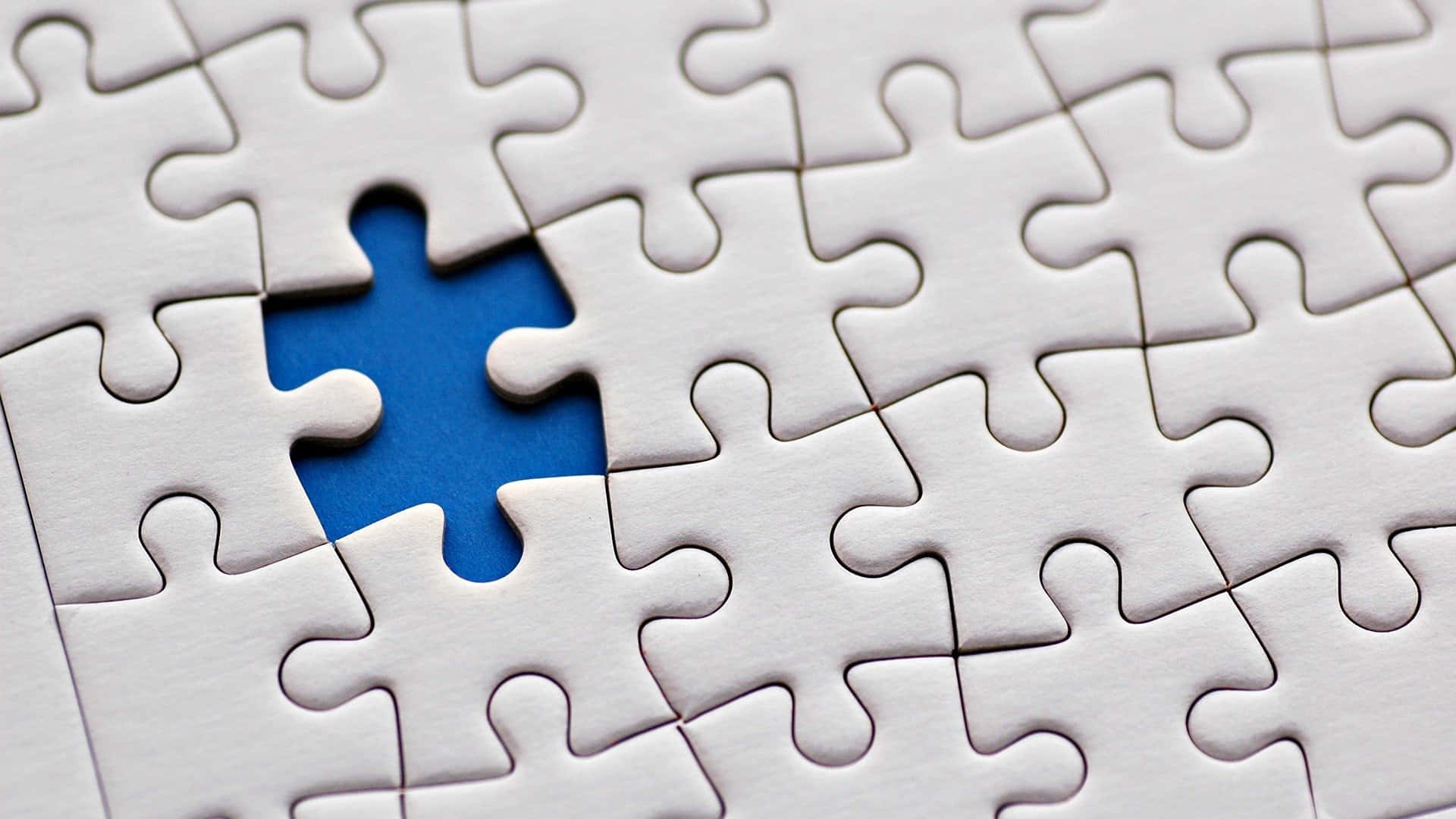 Puzzle 桌布 壁紙 — 白色拼圖塊的特寫，圍繞著一塊缺失的藍色拼圖塊，顯露出一個空洞。