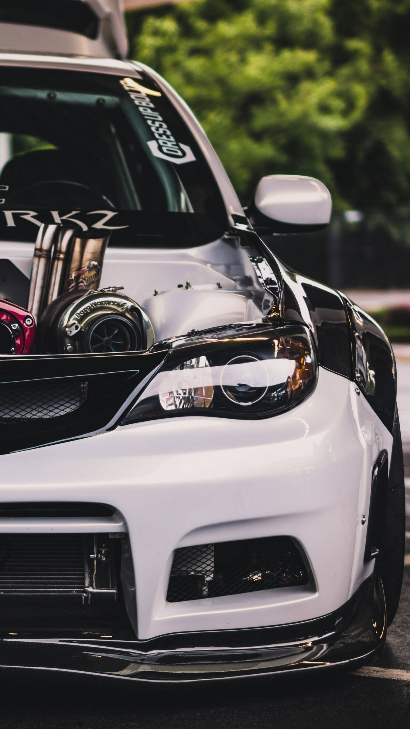 Subaru 桌布 壁紙 — 白色改裝跑車的特寫，帶有外露的渦輪增壓器和賽車貼紙，停放在戶外。