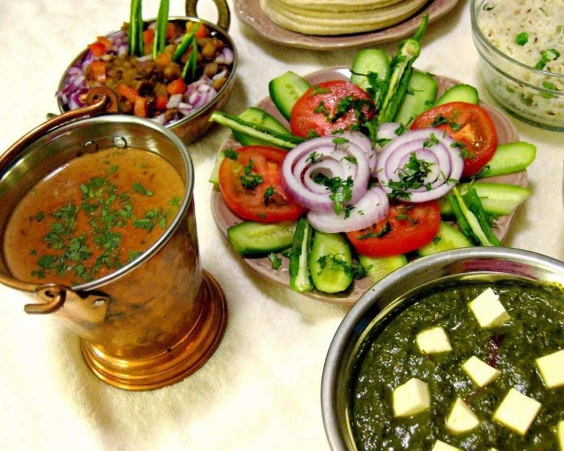 Indian Food 桌布 壁紙 — 白色桌布上擺放著色彩繽紛的印度菜餚，包括奶油雞、菠菜起司和新鮮蔬菜沙拉。
