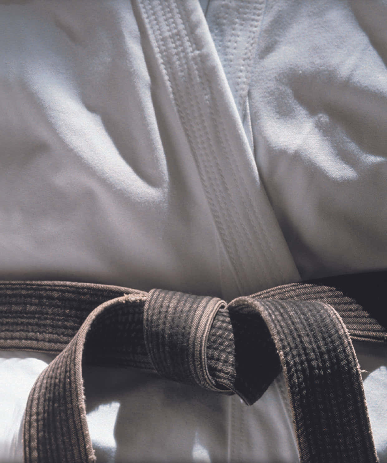 Martial Arts Uniform 桌布 壁紙 — 白色武術道服的近距離特寫，深棕色腰帶在柔和自然光下打結。