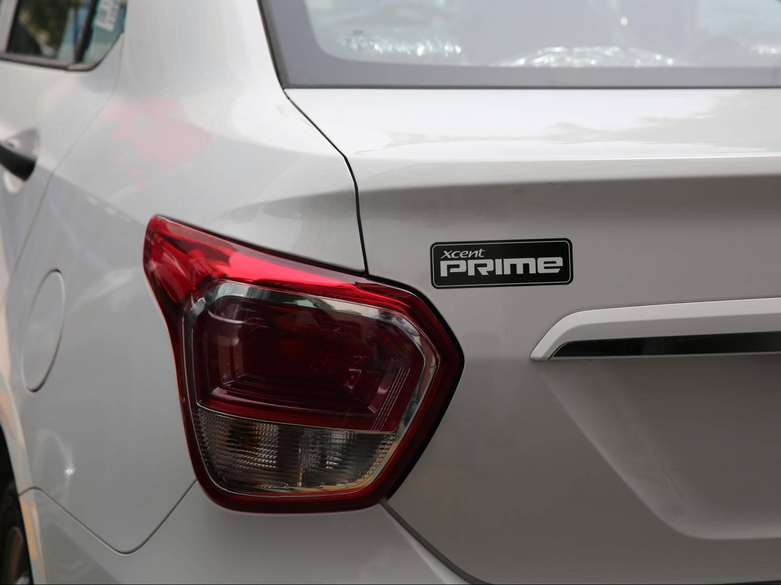 Hyundai 桌布 壁紙 — 白色汽車尾部的特寫，紅色尾燈和 'xcent prime' 徽章在明亮的日光下。
