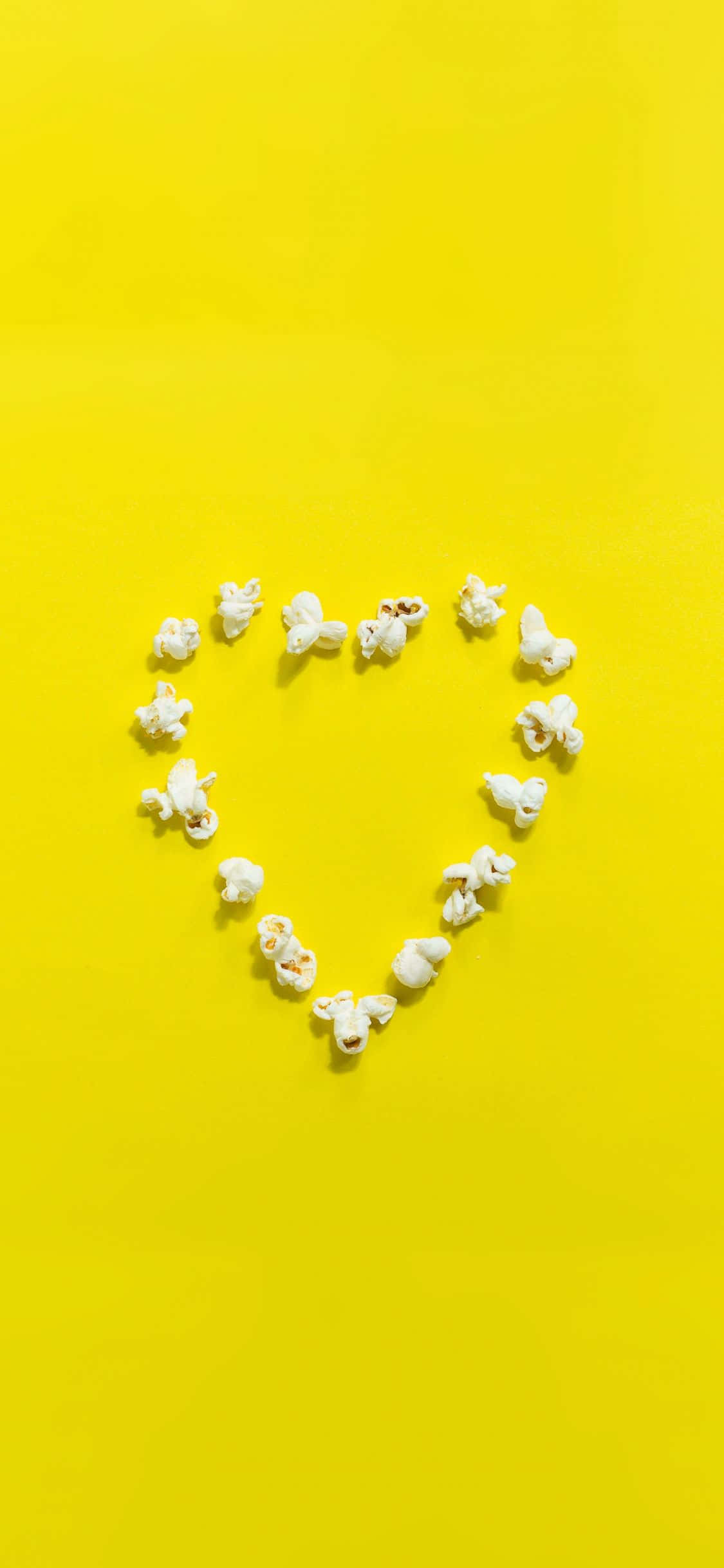 Yellow Heart 桌布 壁紙 — 白色爆米花粒在亮黃色背景上排列成心形。