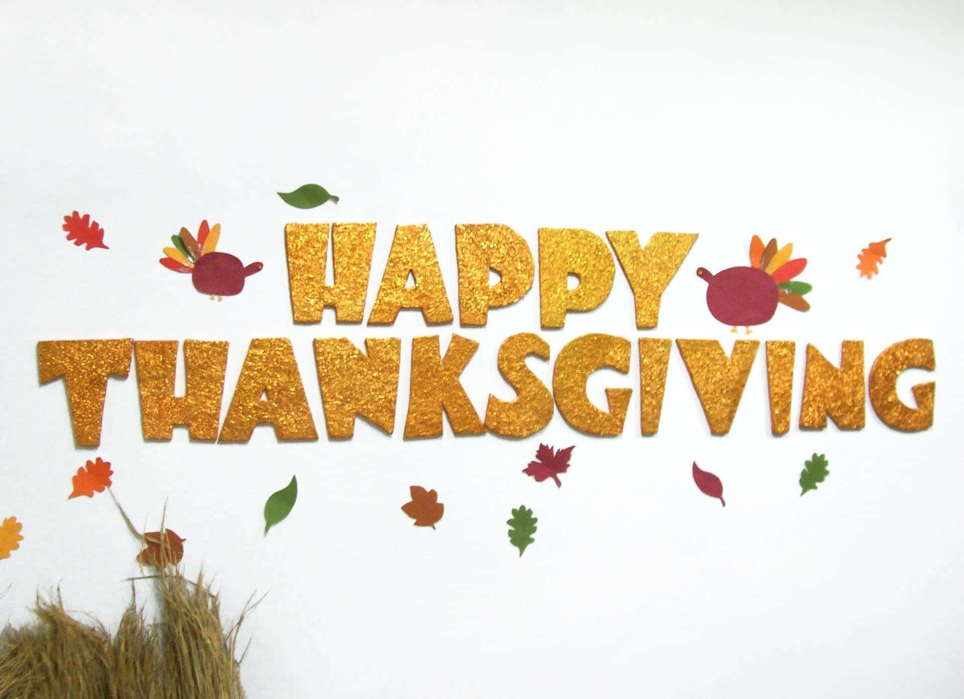 Happy Thanksgiving 桌布 壁紙 — 白色牆上，閃閃發光的金色 'HAPPY THANKSGIVING' 字母，裝飾著紙火雞和秋葉。