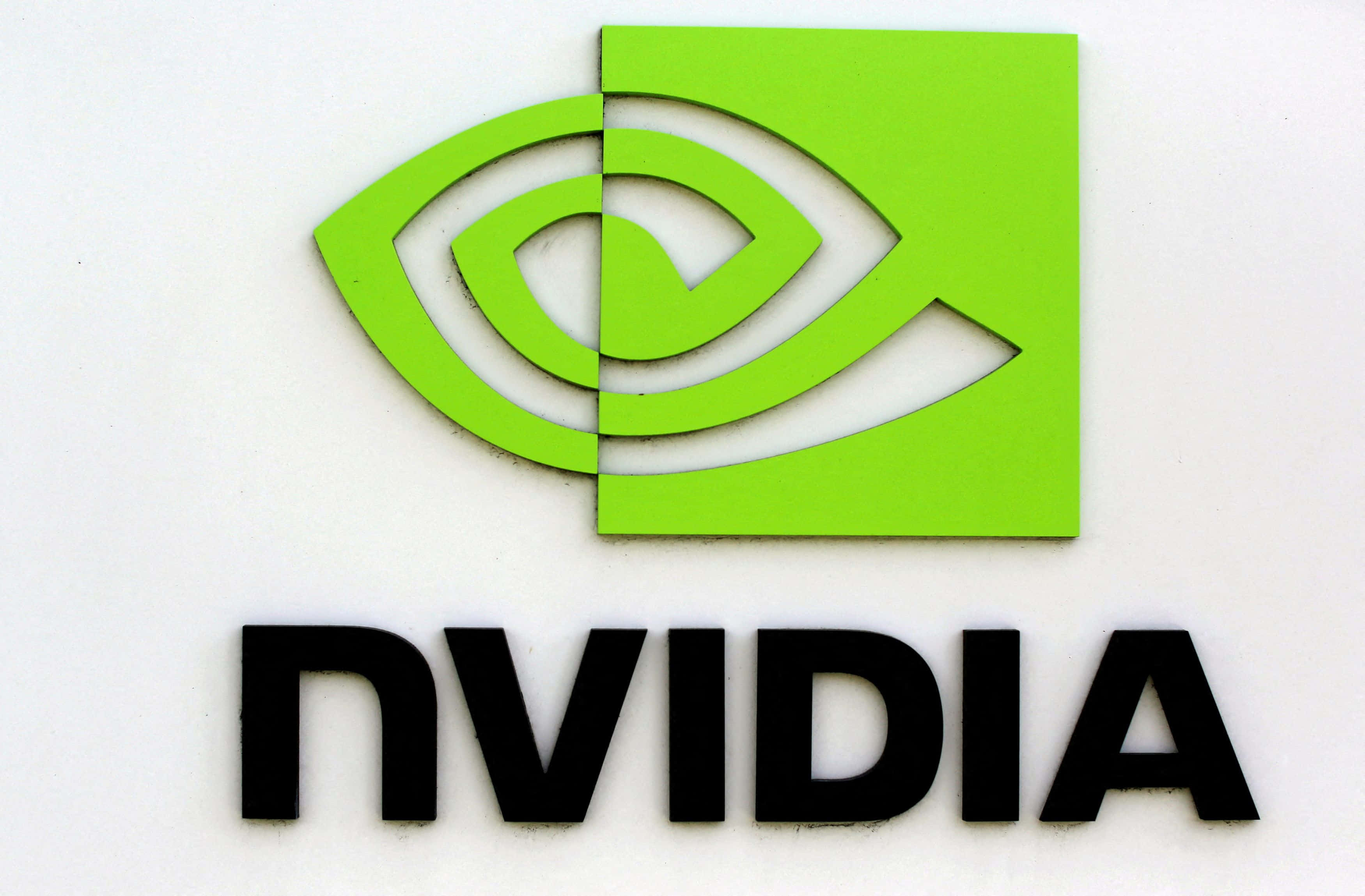 nvidia 桌布 壁紙 — 白色牆壁上亮綠色NVIDIA標誌的特寫，帶有標誌性的眼睛設計和黑色公司名稱。