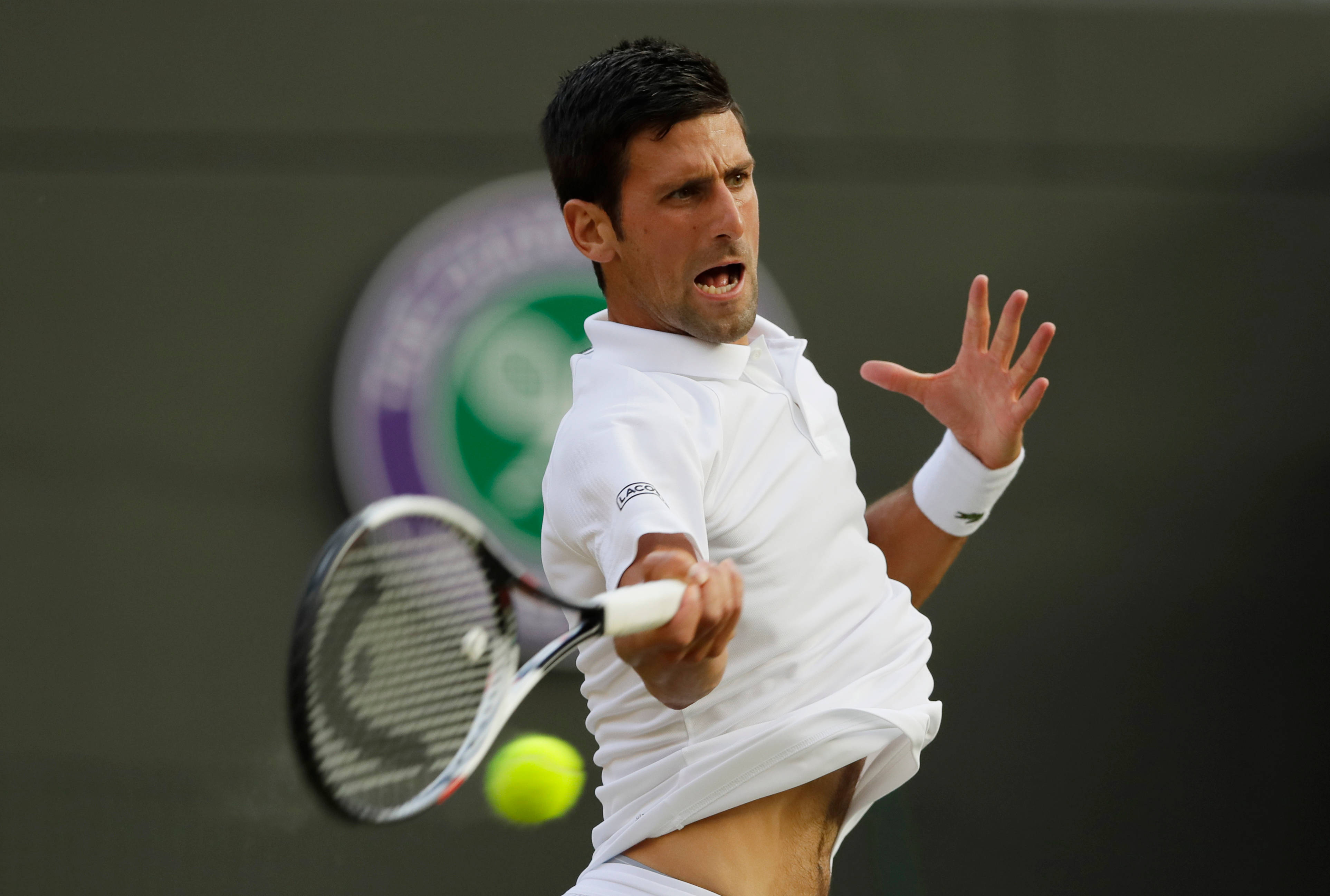 Novak 桌布 壁紙 — 白色球衣的網球選手諾瓦克·喬科維奇在比賽中向前猛衝，以高度專注擊打黃色球。