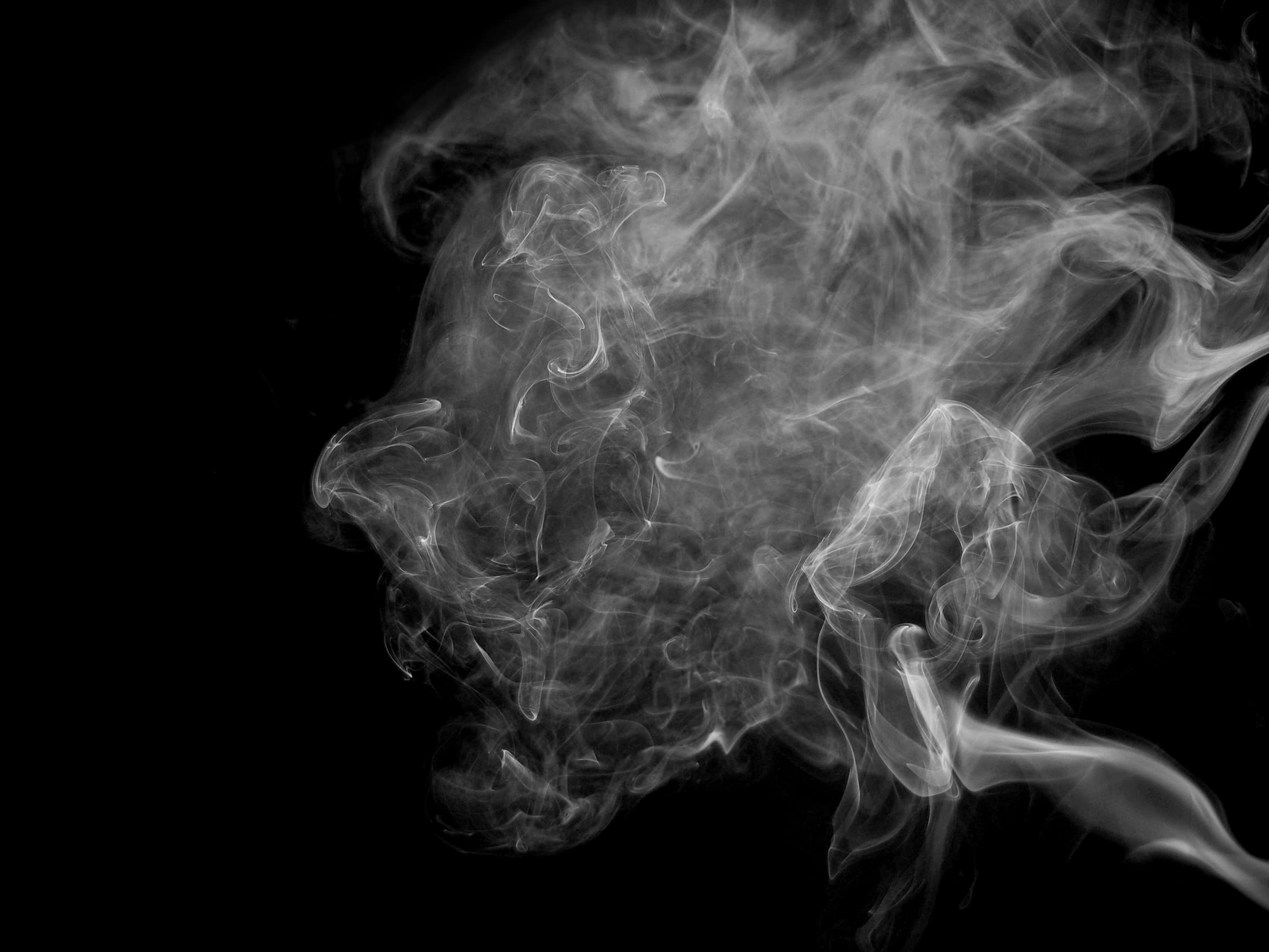 Smoke Clouds 桌布 壁紙 — 白色的縷縷輕煙在純黑背景上動態地旋轉，形成鬼魅般的抽象形態。