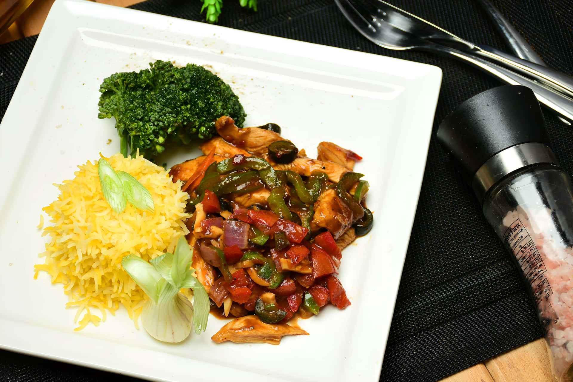 Chicken Chilli Dry with rice on a plate 壁紙 — 白色盤子上放有醬汁雞肉炒配紅綠燈籠椒和洋蔥，旁邊有黃色飯和蒸青花菜。