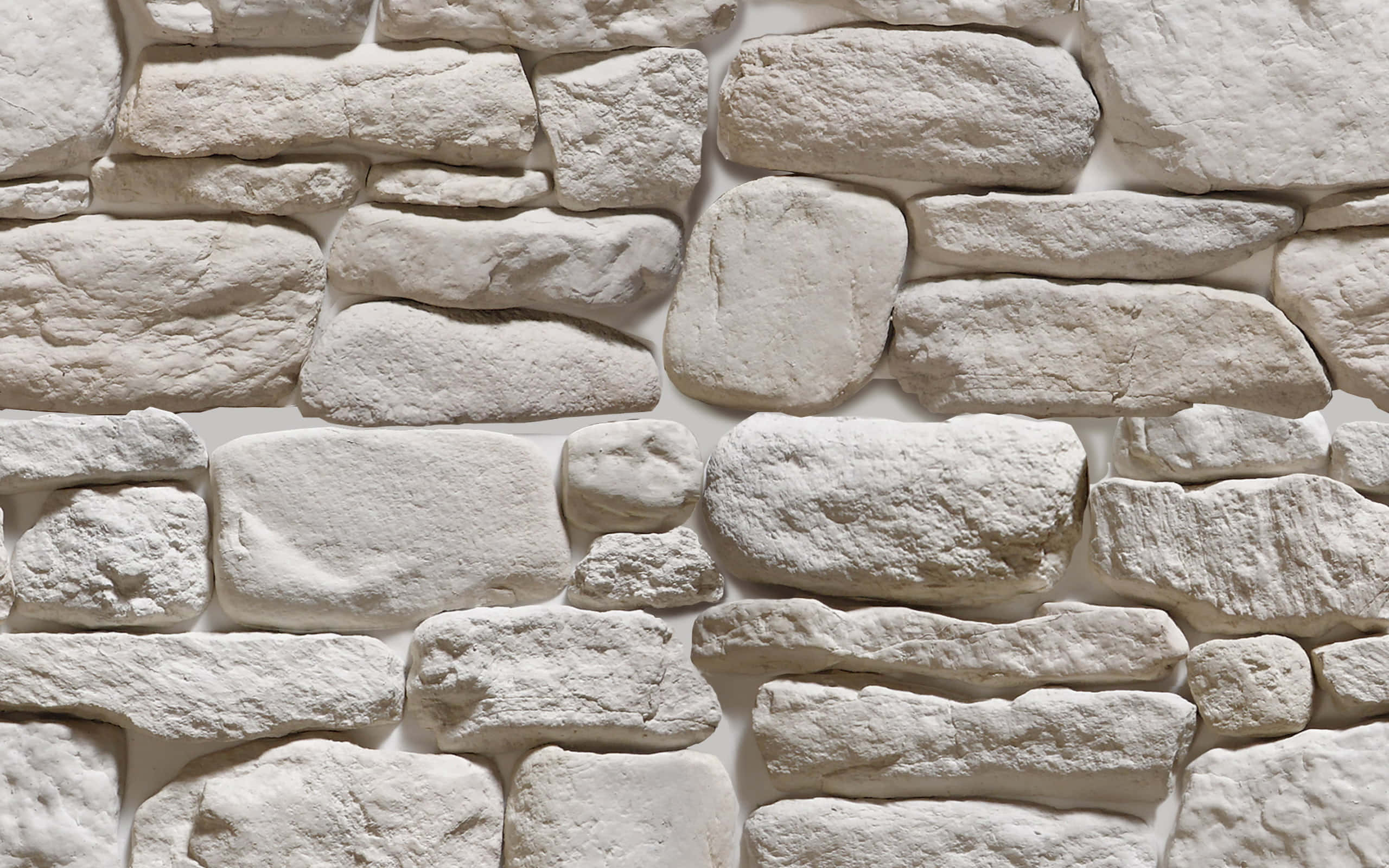 Stone Wall 桌布 壁紙 — 白色石牆特寫，表面帶有紋理，由不規則形狀的石塊組成，並有柔和陰影。