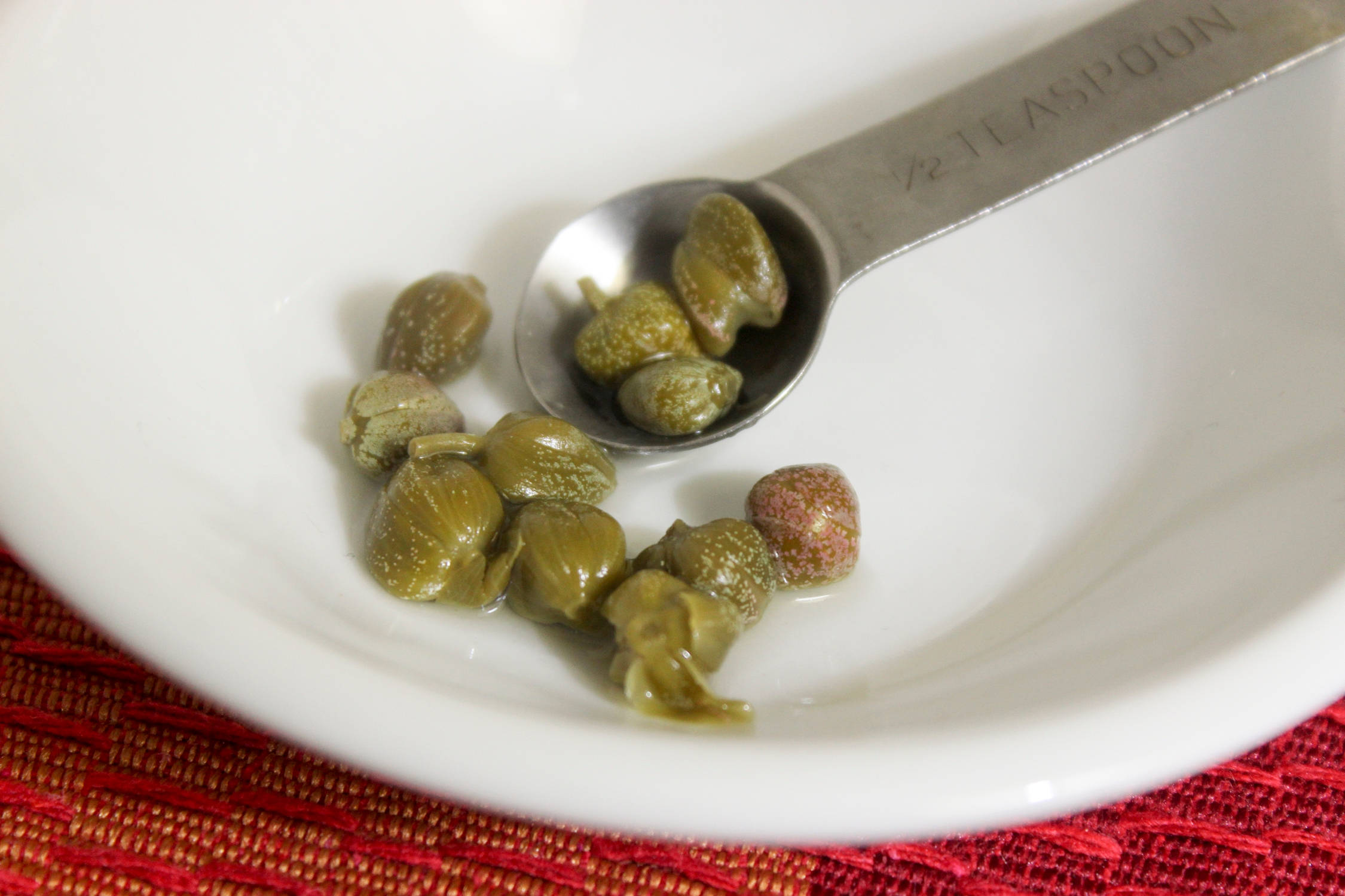plants 桌布 壁紙 — 白色碗中的綠色酸豆特寫，半茶匙量匙盛著一些酸豆。