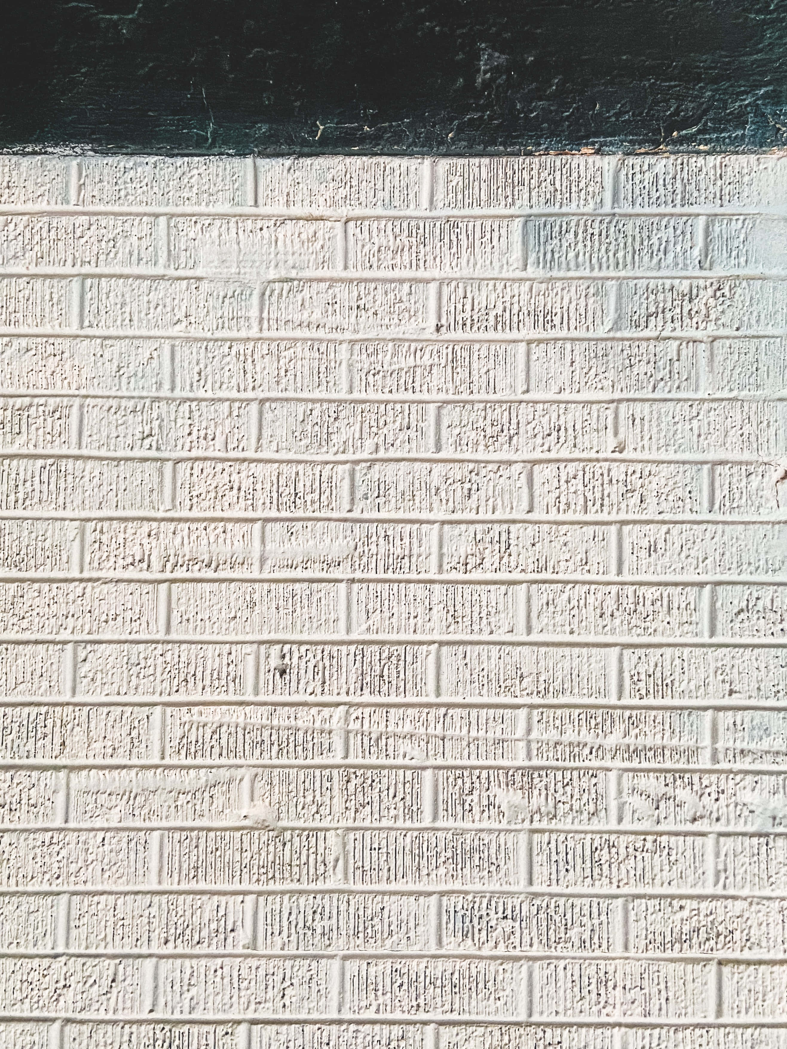 White Brick Wall 桌布 壁紙 — 白色磚牆的特寫，頂部有一條黑色木樑，顯示出風化的質感。