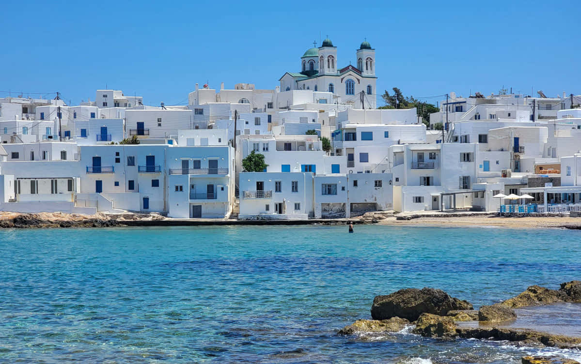 Greek Island 桌布 壁紙 — 白色粉刷的希臘村莊坐落在懸崖上，俯瞰著碧藍色的大海，天空清澈湛藍。