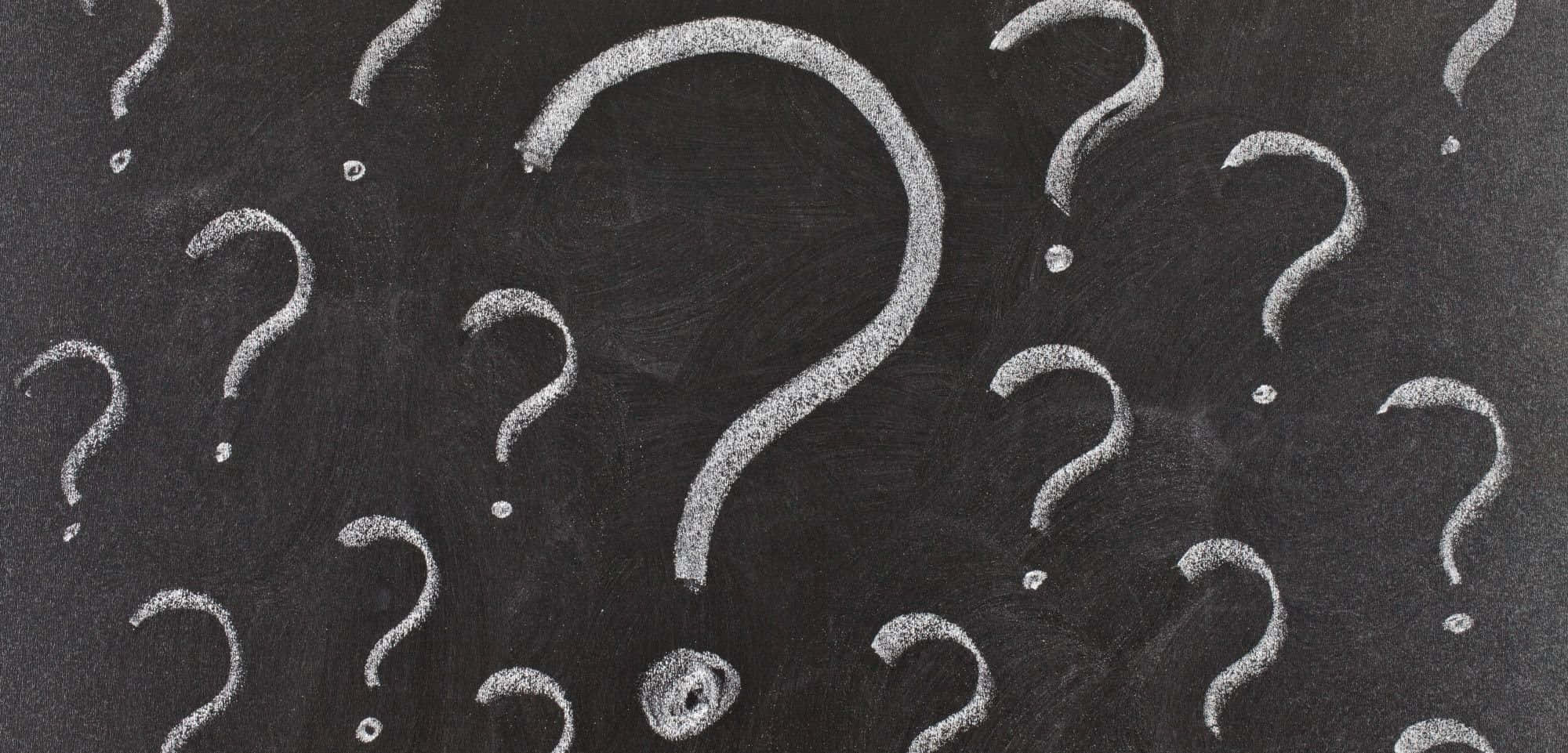 Question Mark 桌布 壁紙 — 白色粉筆問號散落在帶有紋理顆粒的深色黑板表面上。