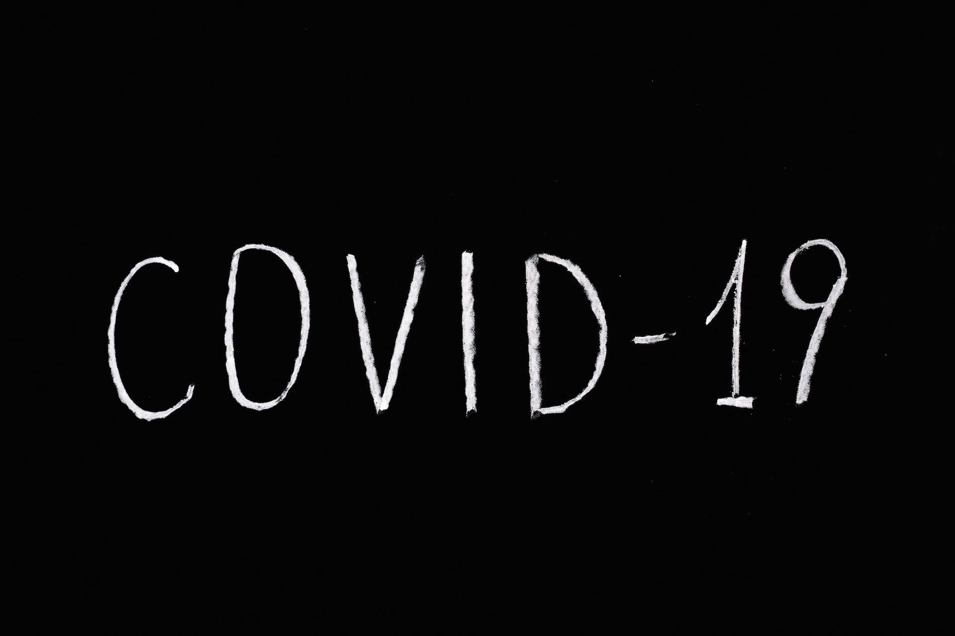 黑色 桌布 壁紙 — 白色粉筆在純黑背景上寫下的COVID-19字樣。