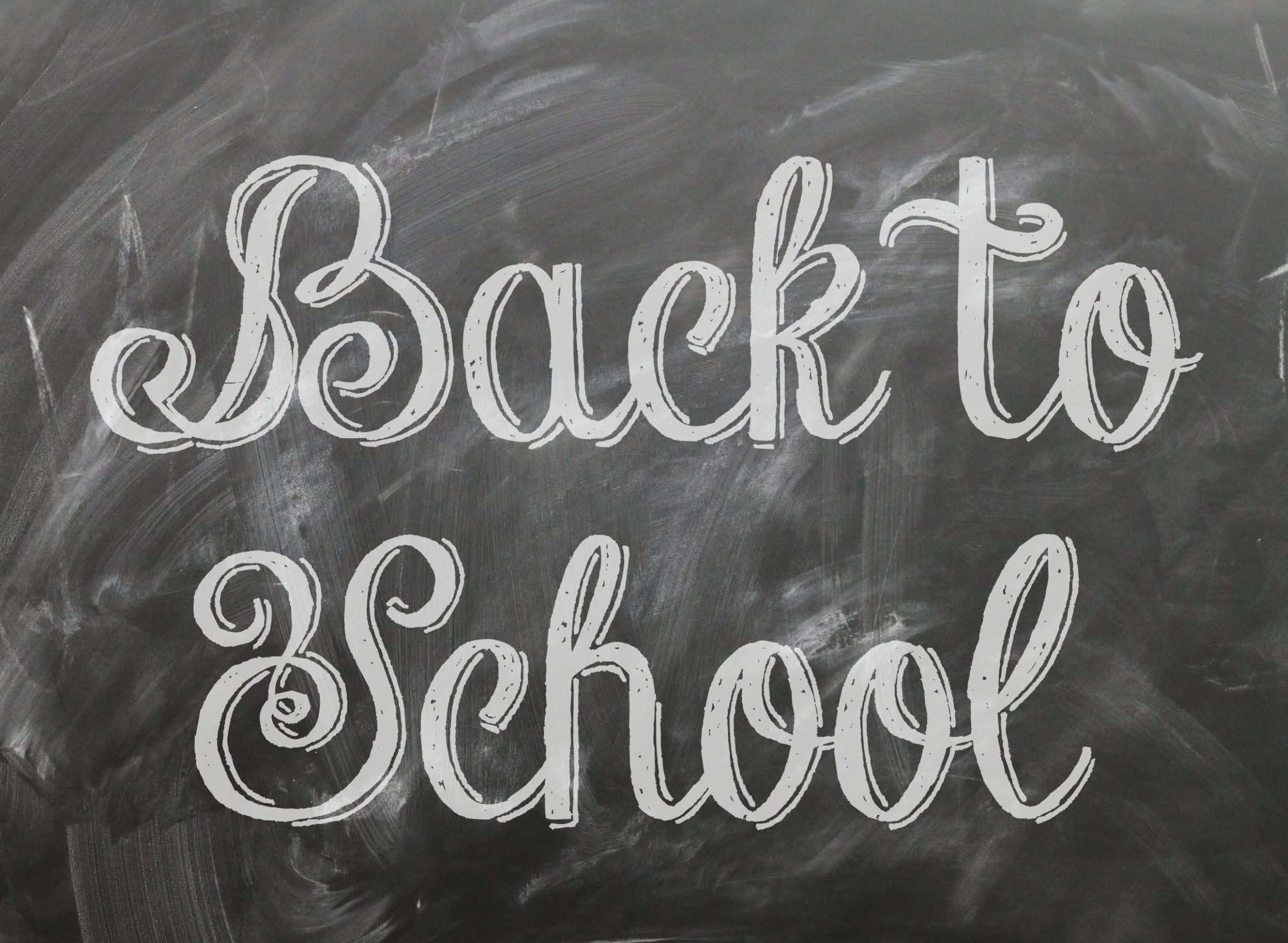 Back To School 桌布 壁紙 — 白色粉筆字在紋理深灰色黑板表面上寫著「Back to School」。