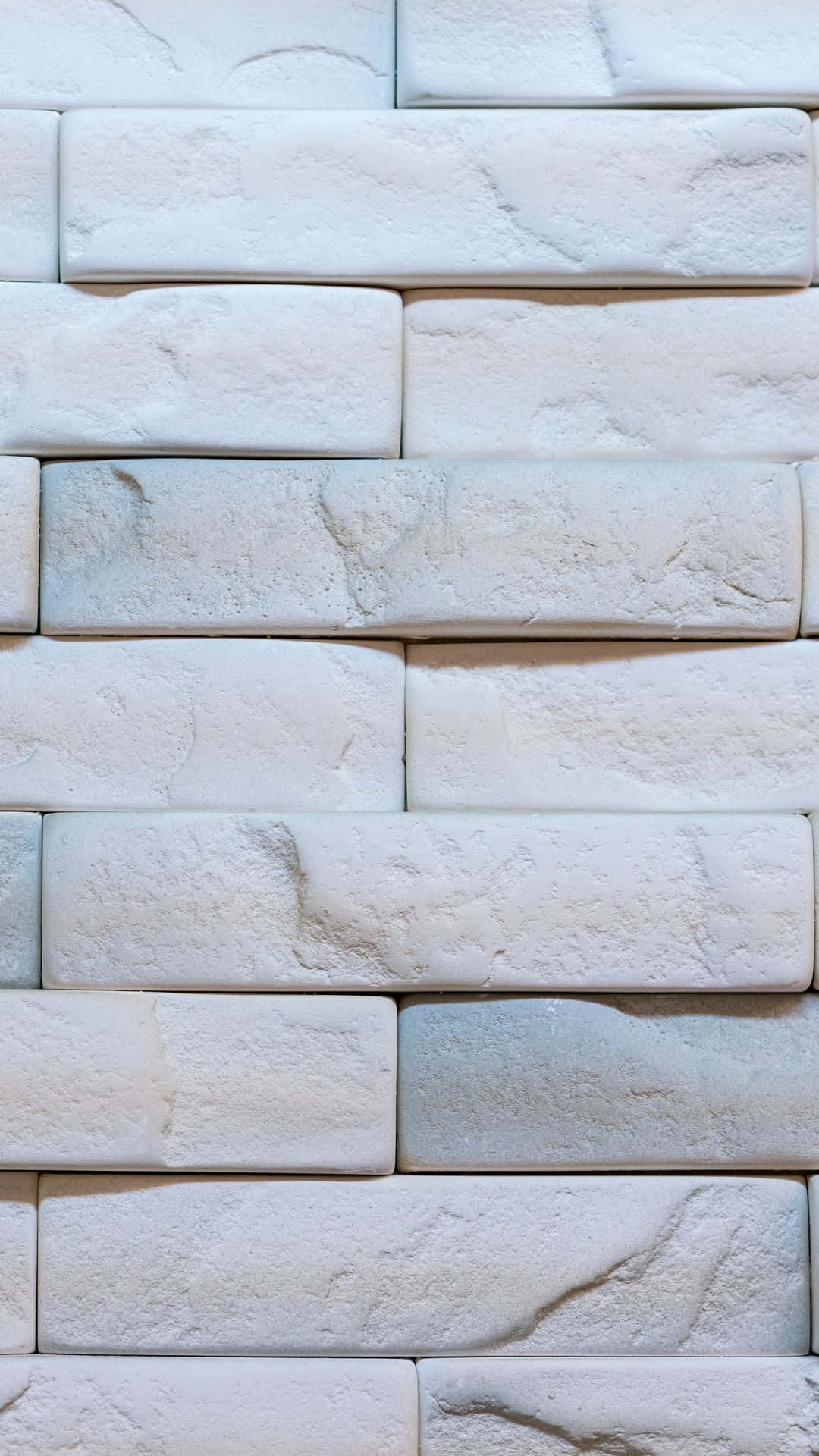 White Brick 桌布 壁紙 — 白色紋理石磚的特寫，以交錯的牆壁圖案排列，帶有柔和陰影。