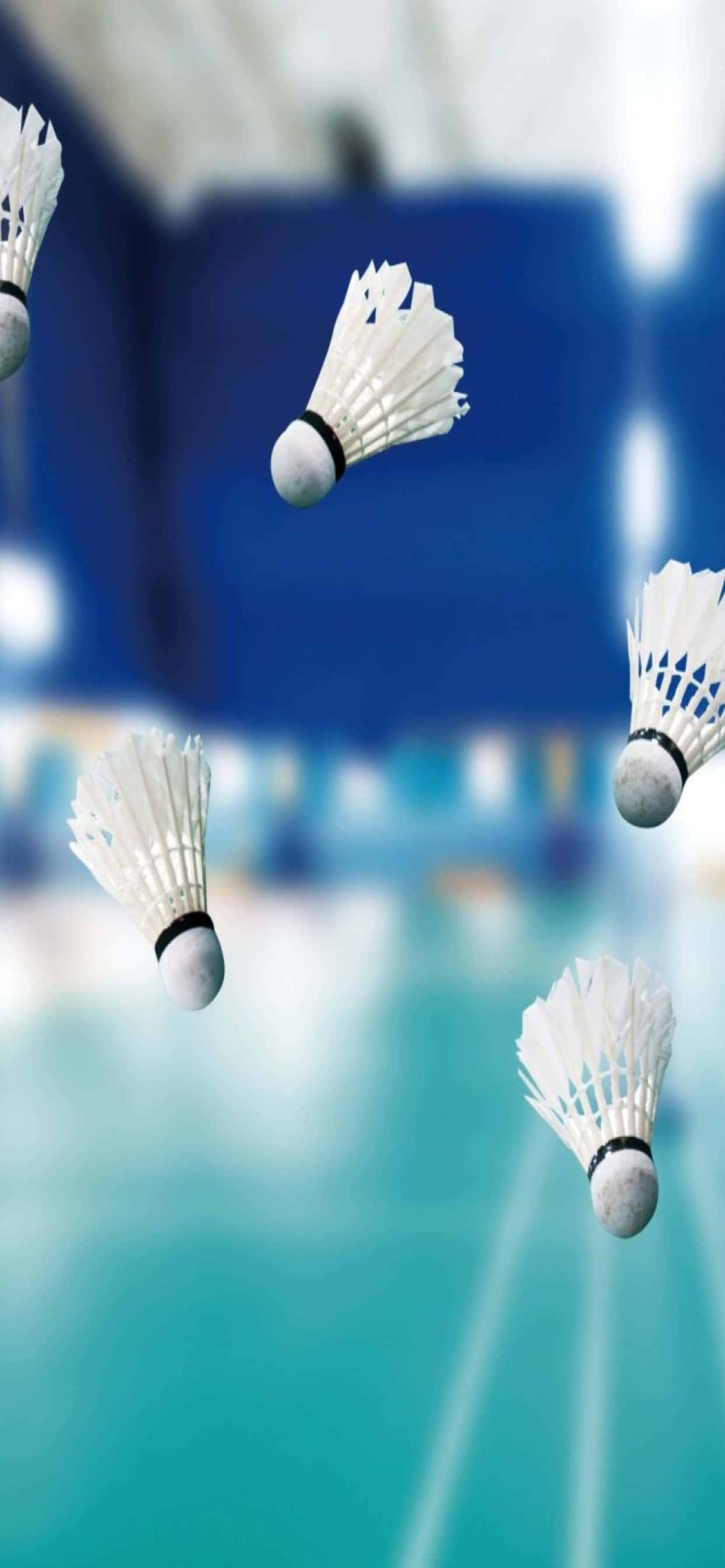 iPhone Xs Max Badminton 桌布 壁紙 — 白色羽毛球在模糊的藍色和藍綠色羽毛球場背景下動態飛翔。