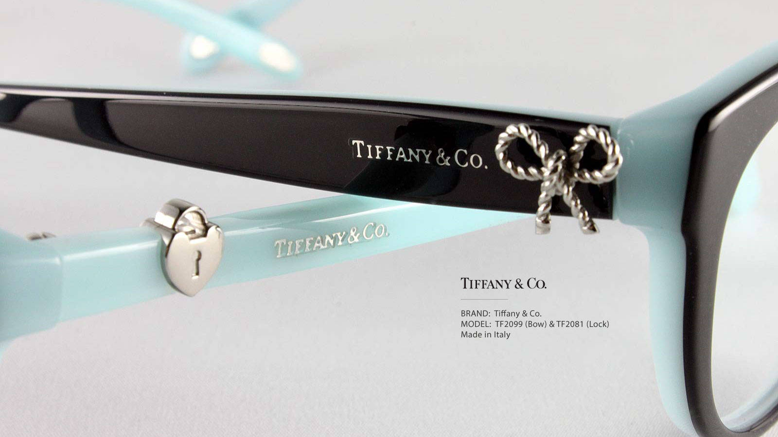 品牌 桌布 壁紙 — 白色背景上，Tiffany & Co. 眼鏡的特寫，配有淺藍色鏡框、銀色蝴蝶結和心形吊飾。