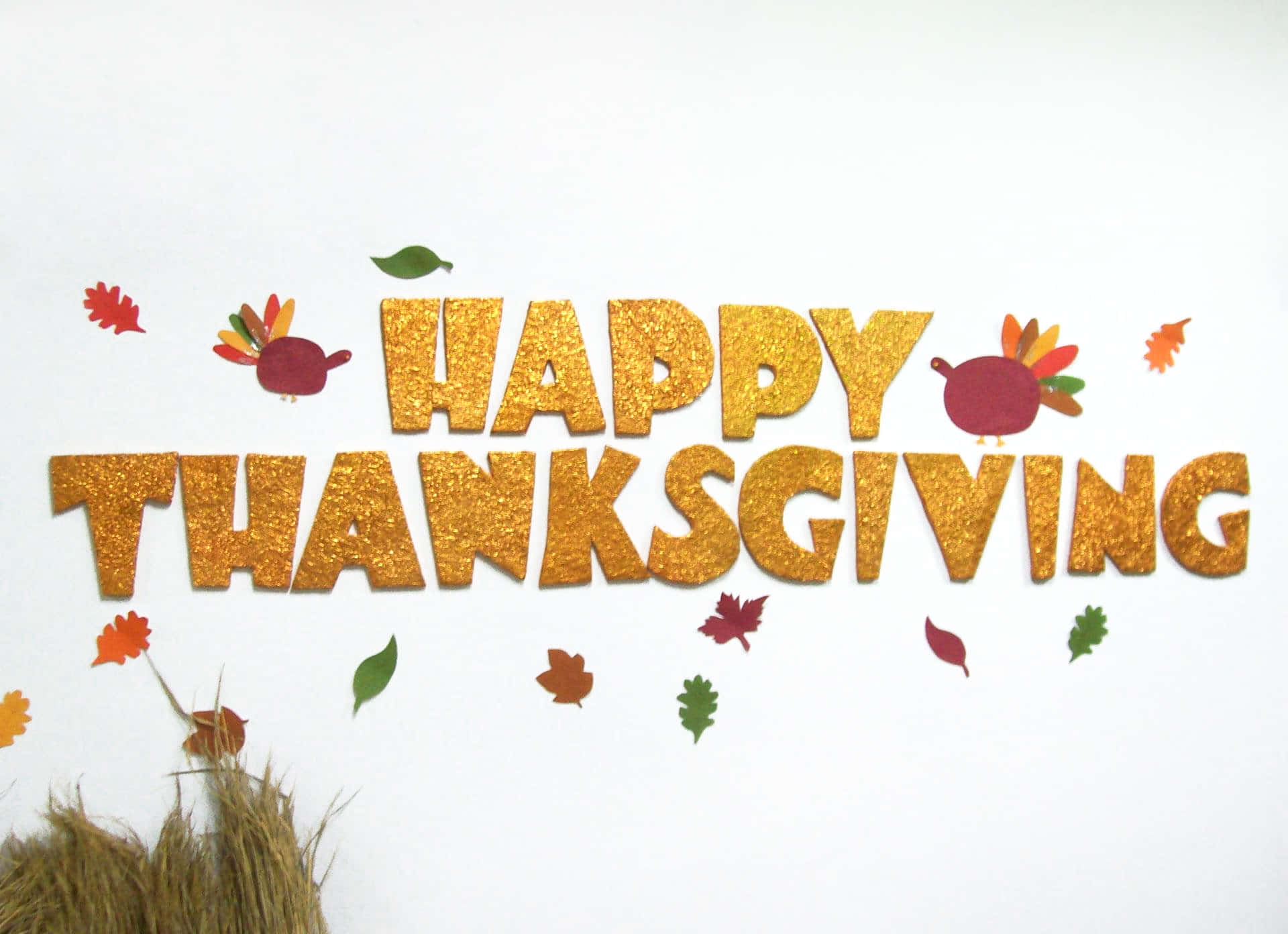 節日 桌布 壁紙 — 白色背景上，金色閃亮的「HAPPY THANKSGIVING」字母，裝飾著紙火雞和秋葉。