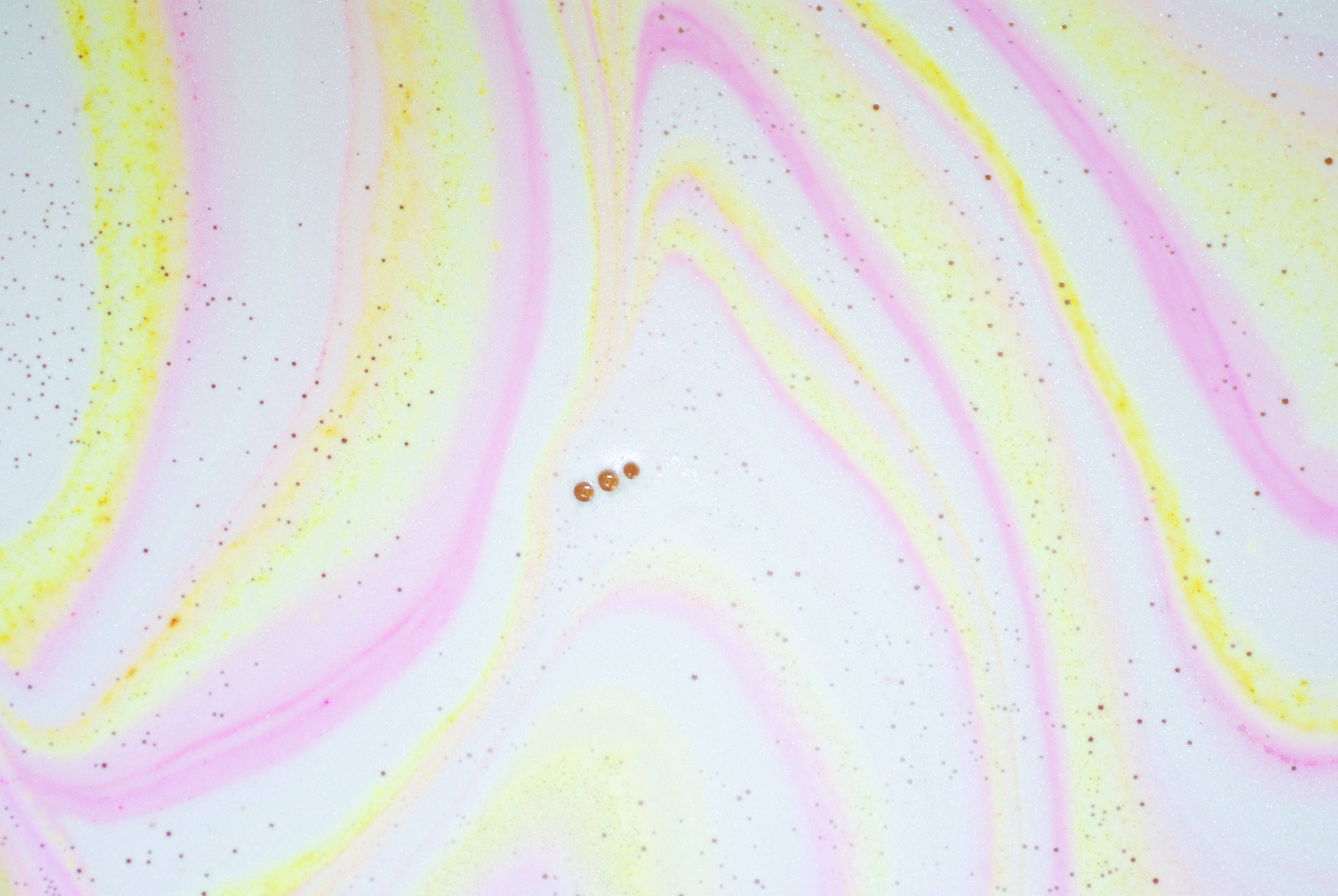Lush 桌布 壁紙 — 白色背景上帶有閃亮斑點和微小銅珠的柔和粉紅色和黃色漩渦。