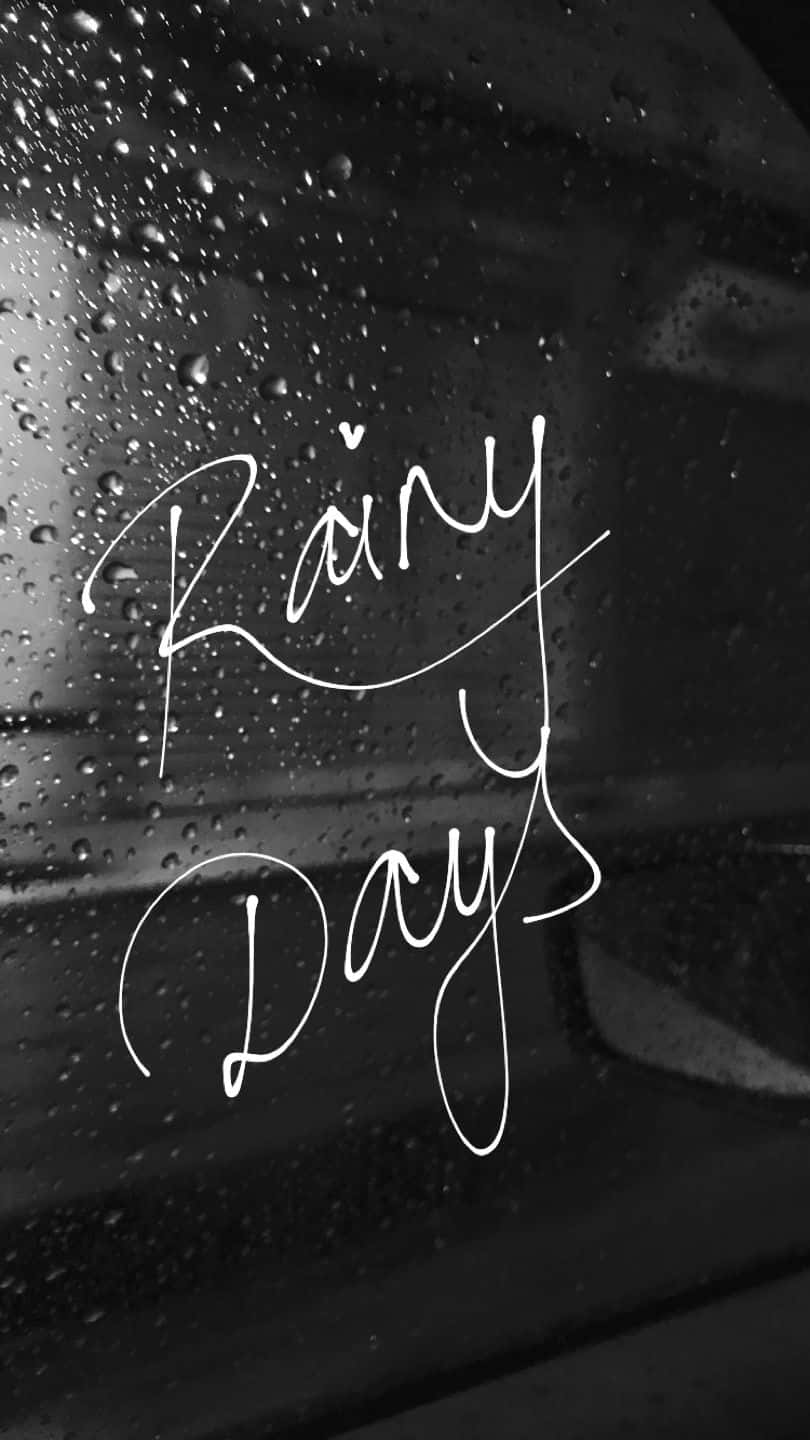 桌布 壁紙 — 白色草書文字「Rainy Days」在佈滿雨滴的黑色車窗上發光。
