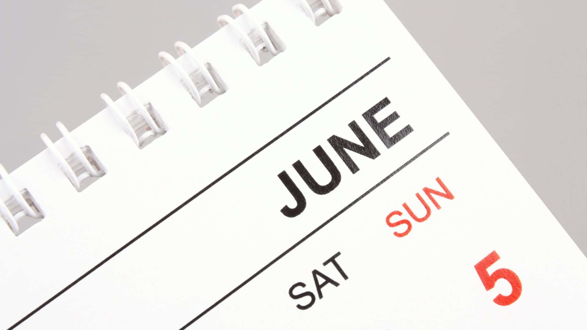 June 桌布 壁紙 — 白色螺旋裝訂日曆頁的特寫，顯示6月5日，星期日文字為紅色，星期六文字為黑色。
