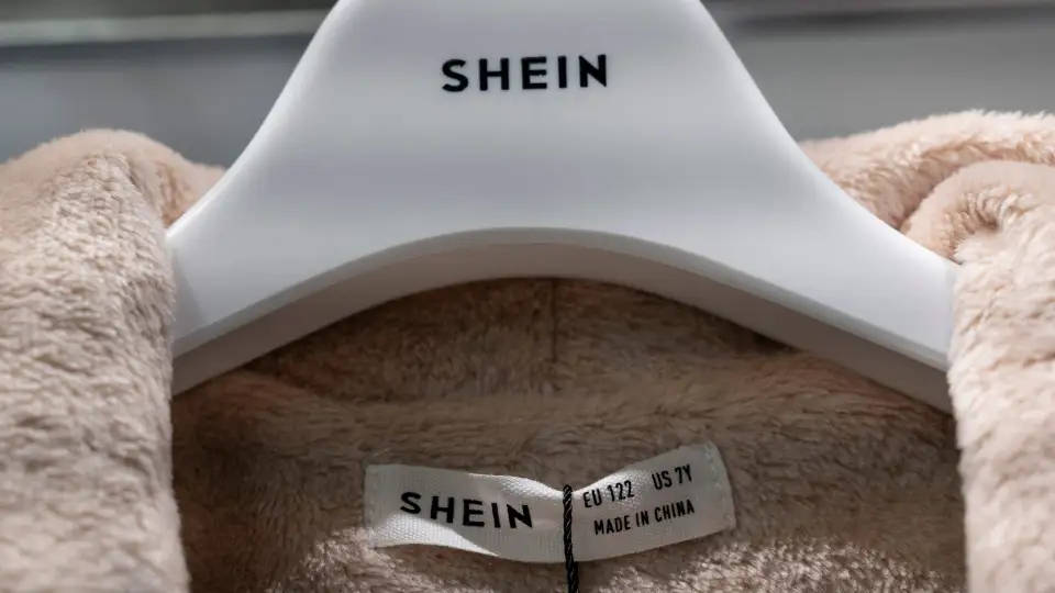 Shein 桌布 壁紙 — 白色衣架上的米色絨毛衣物特寫，可見SHEIN品牌標籤和尺寸細節。