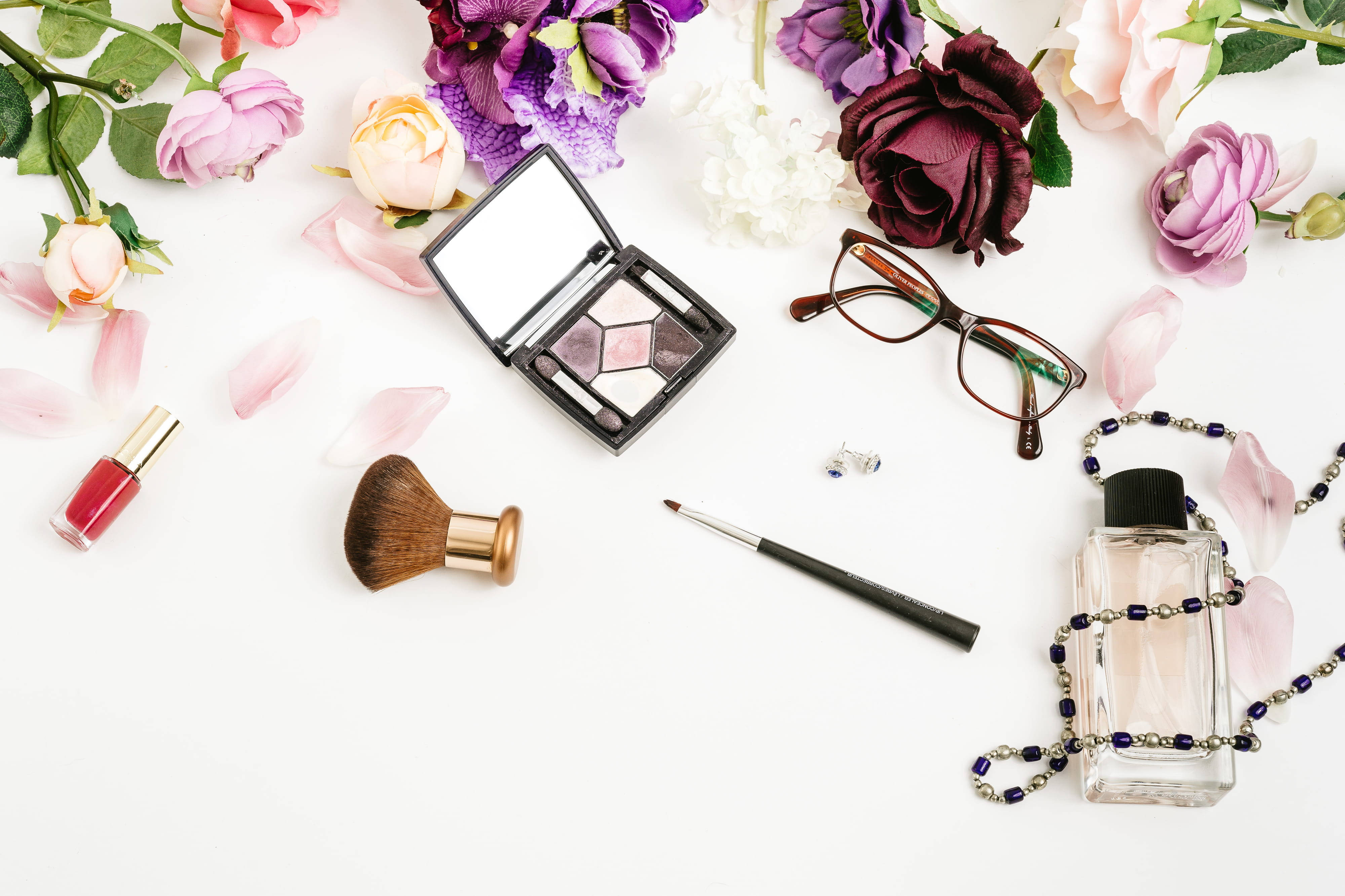 Makeup 桌布 壁紙 — 白色表面上化妝品和色彩繽紛花朵的平鋪佈置。