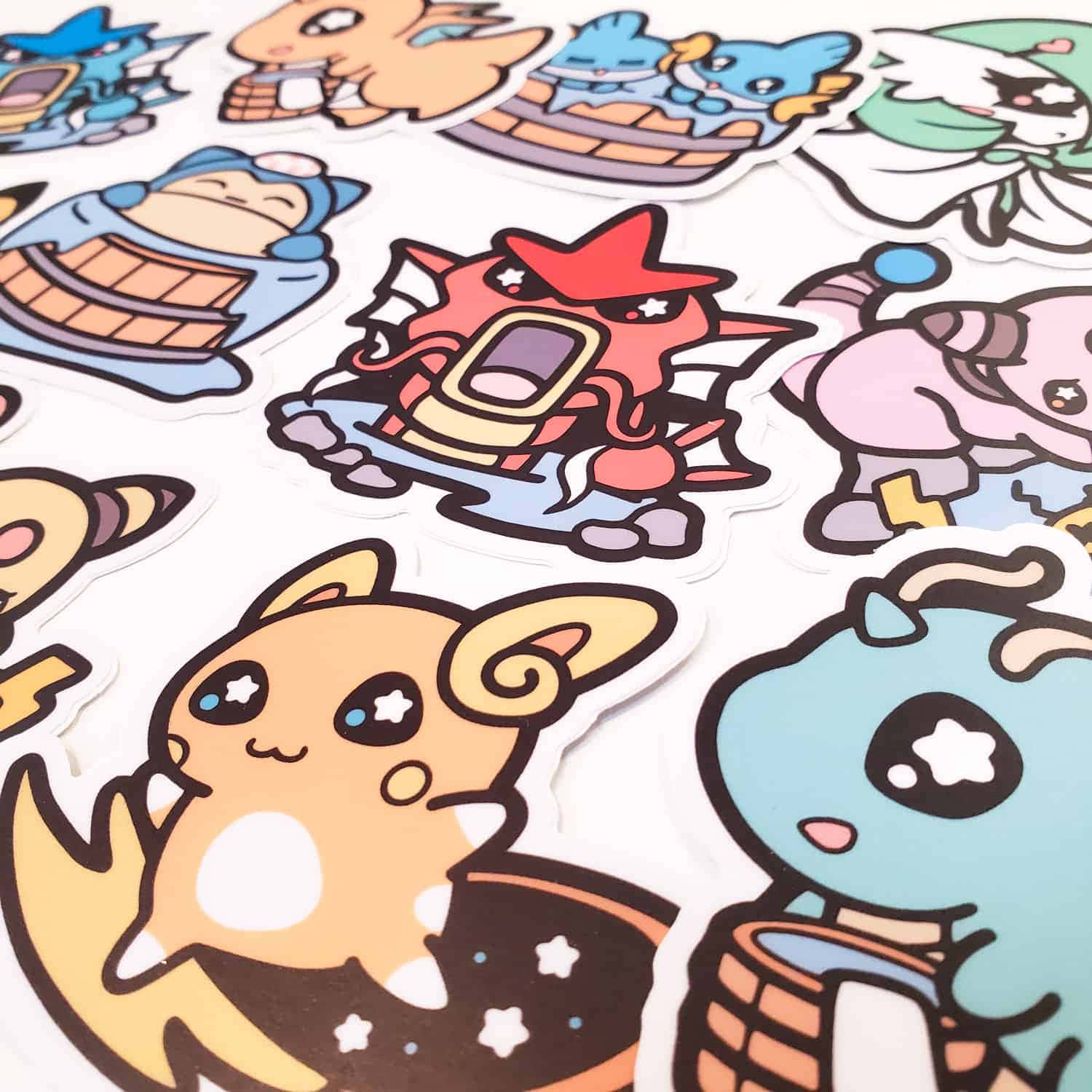 Pokemon Stickers 桌布 壁紙 — 白色表面上散落著色彩繽紛的卡通風格寶可夢貼紙特寫，包括皮卡丘等角色，採用可愛的Q版風格。