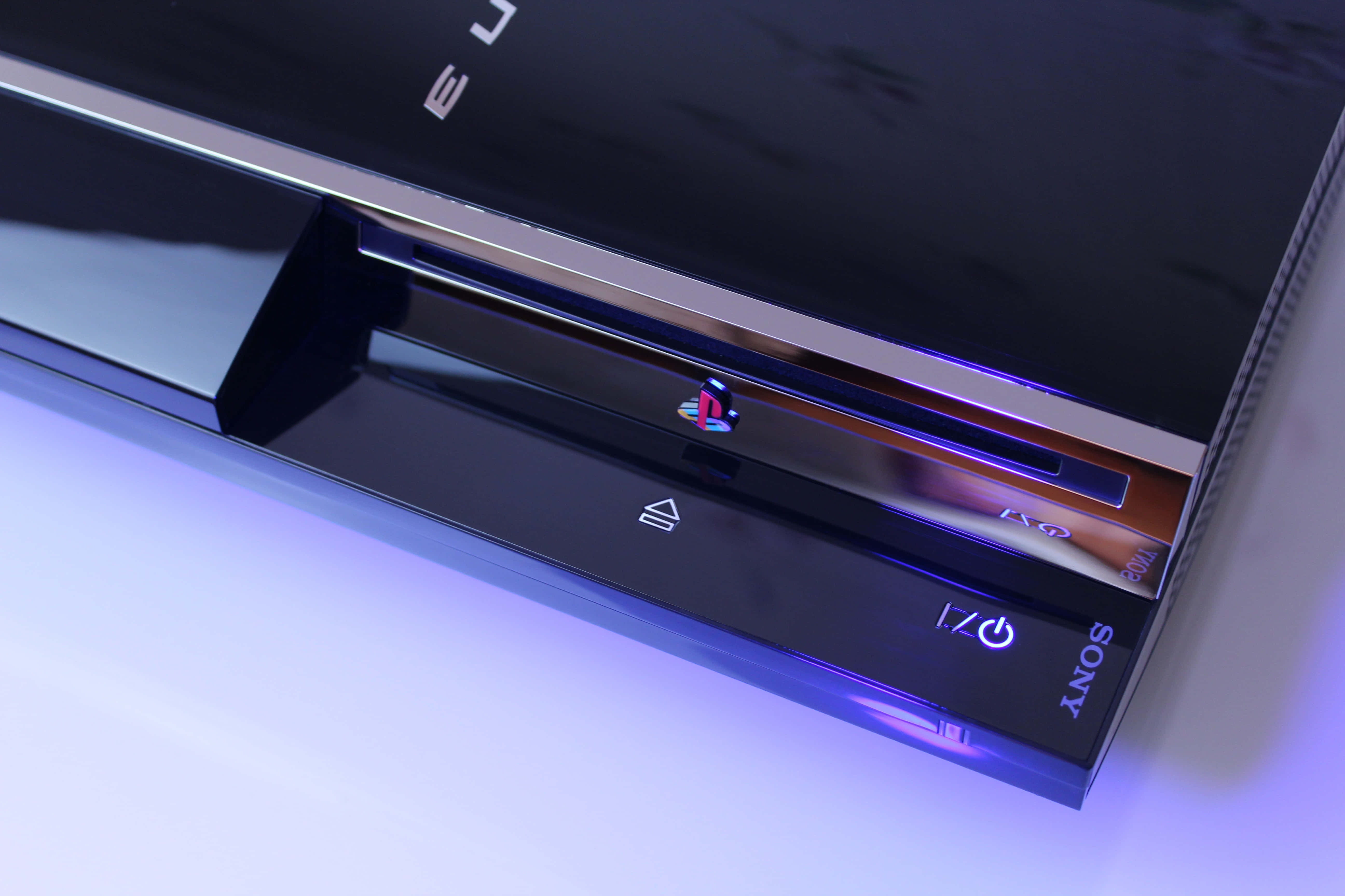 Gaming Consoles 桌布 壁紙 — 白色表面上黑色PlayStation 3主機發出紫色LED燈光的特寫。