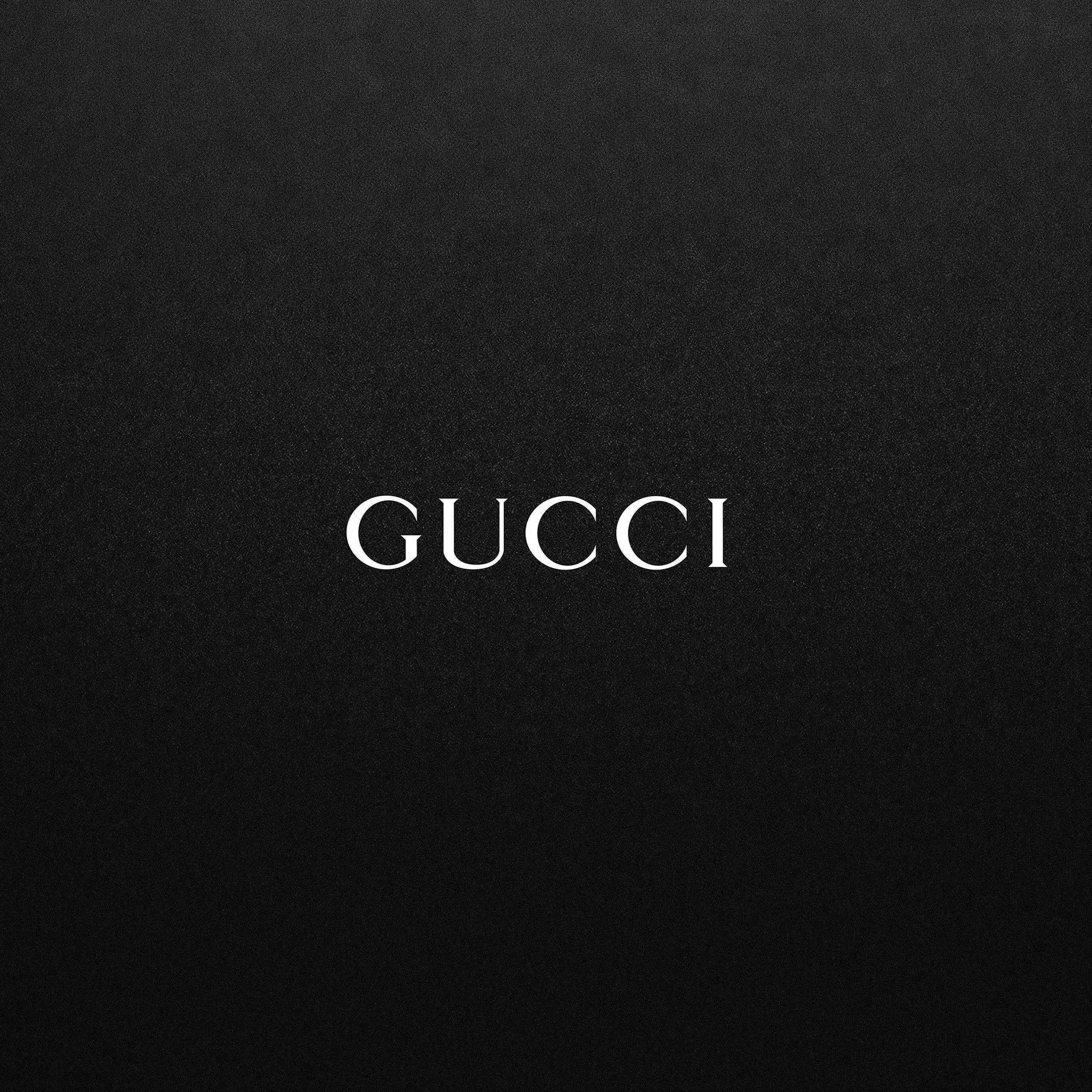 Gucci 桌布 壁紙 — 白色襯線字體 GUCCI 置中於有紋理的黑色布料背景上。