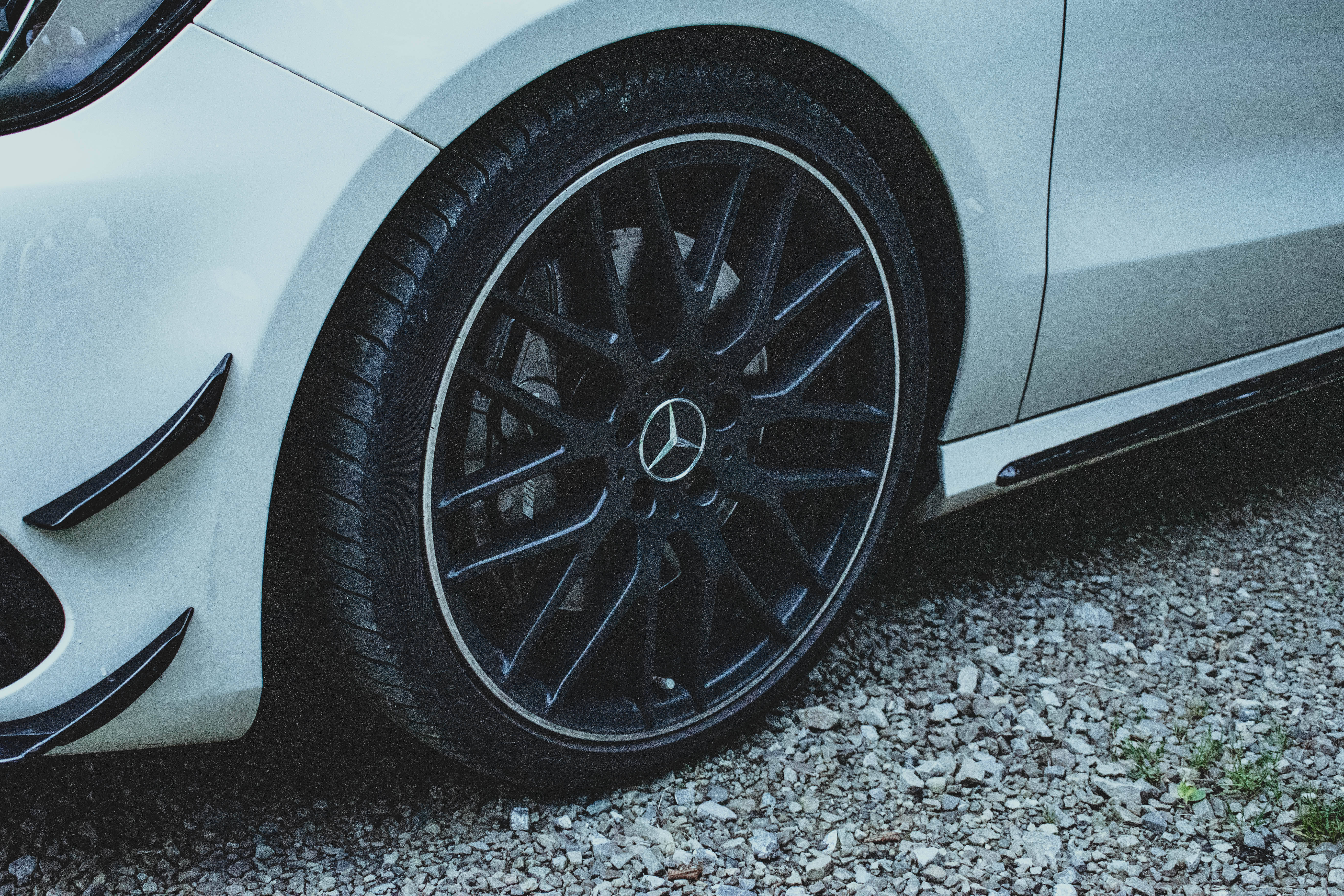 Mercedes Amg 桌布 壁紙 — 白色賓士汽車的黑色多輻輪轂在碎石地面上的特寫。