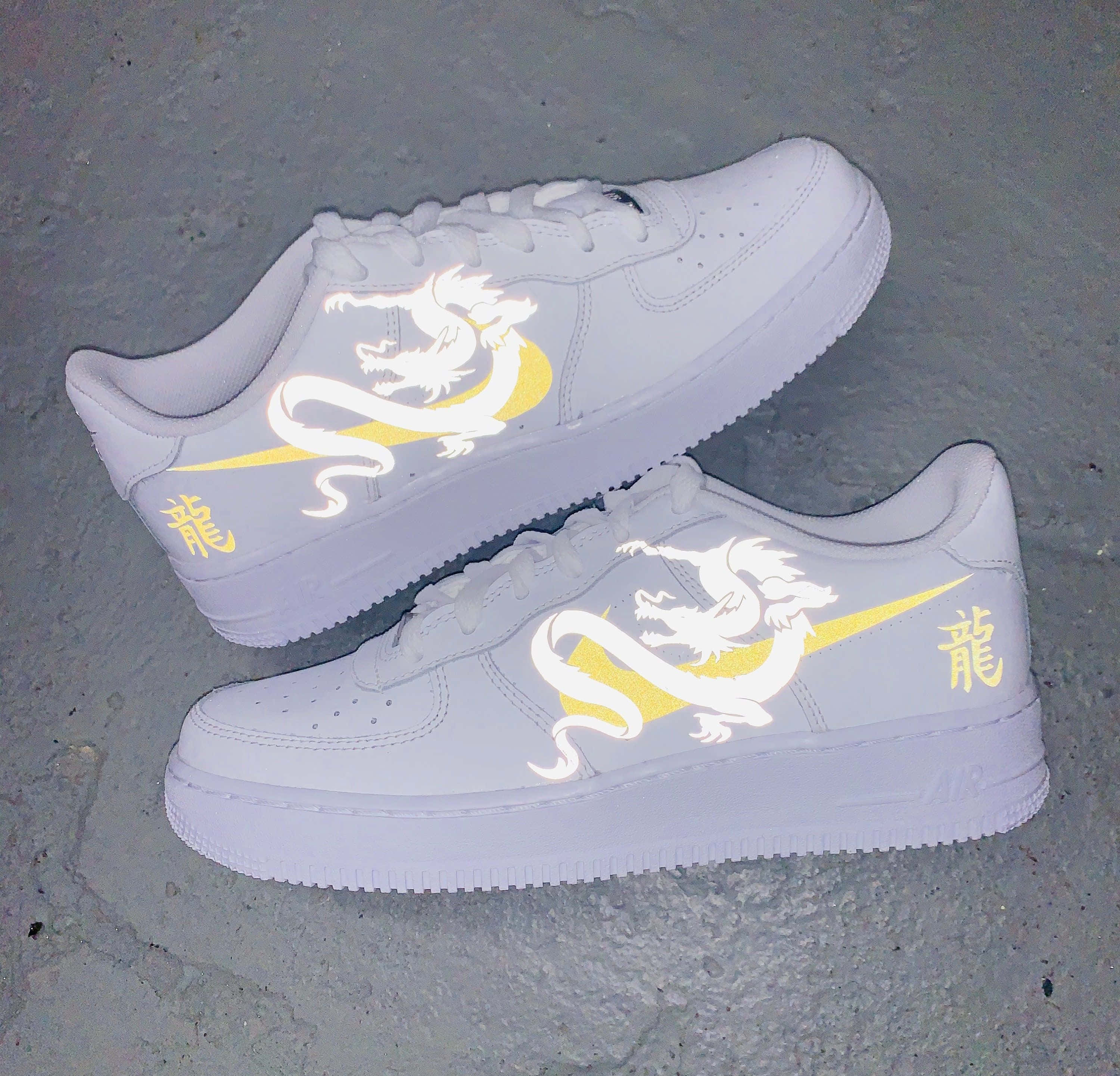 Nike Air Force 桌布 壁紙 — 白色運動鞋帶有發光龍和中文文字設計，放置在紋理灰色混凝土表面上。