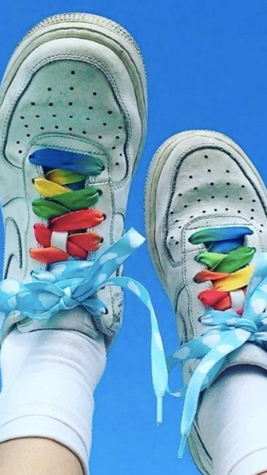 Nike 桌布 壁紙 — 白色運動鞋特寫，配有彩虹鞋帶和藍色波點絲帶，背景是明亮的藍天。