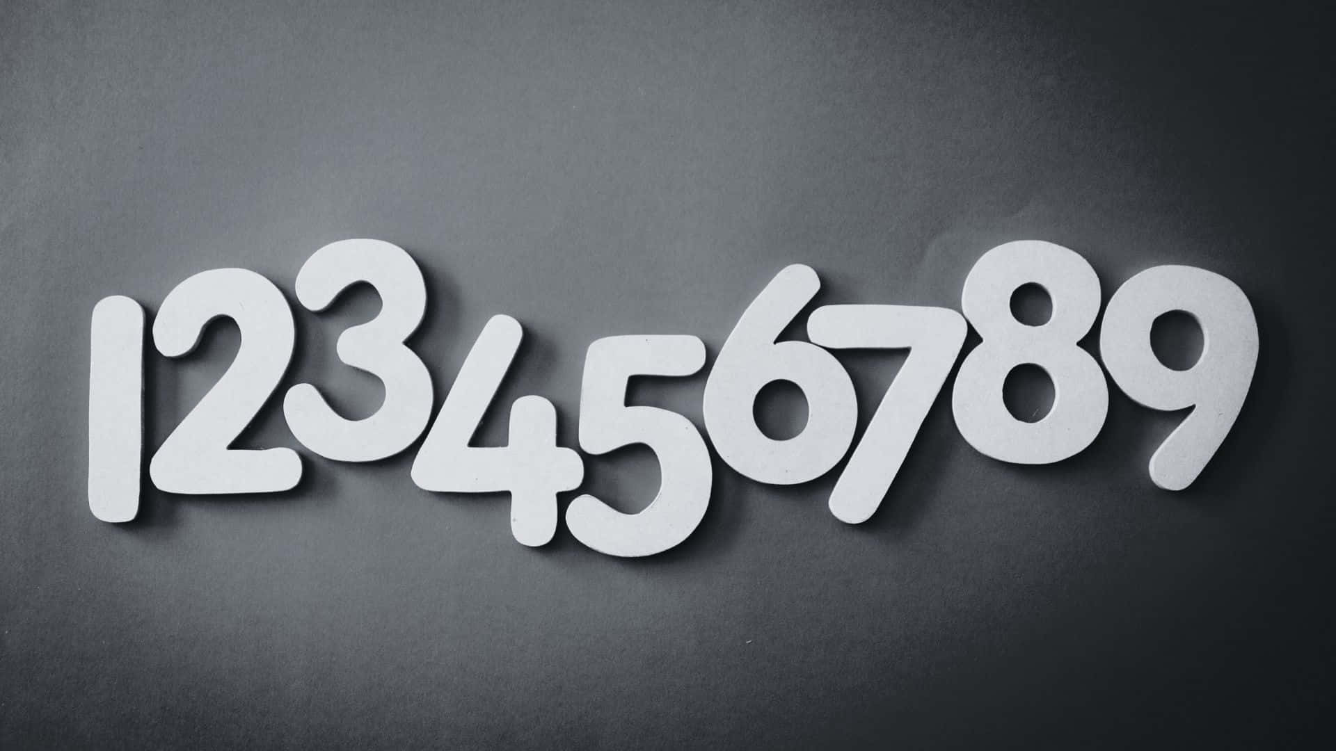 Black And White Number 桌布 壁紙 — 白色鏤空數字一到九排列在一行，位於深灰色紋理表面上，帶有柔和陰影。