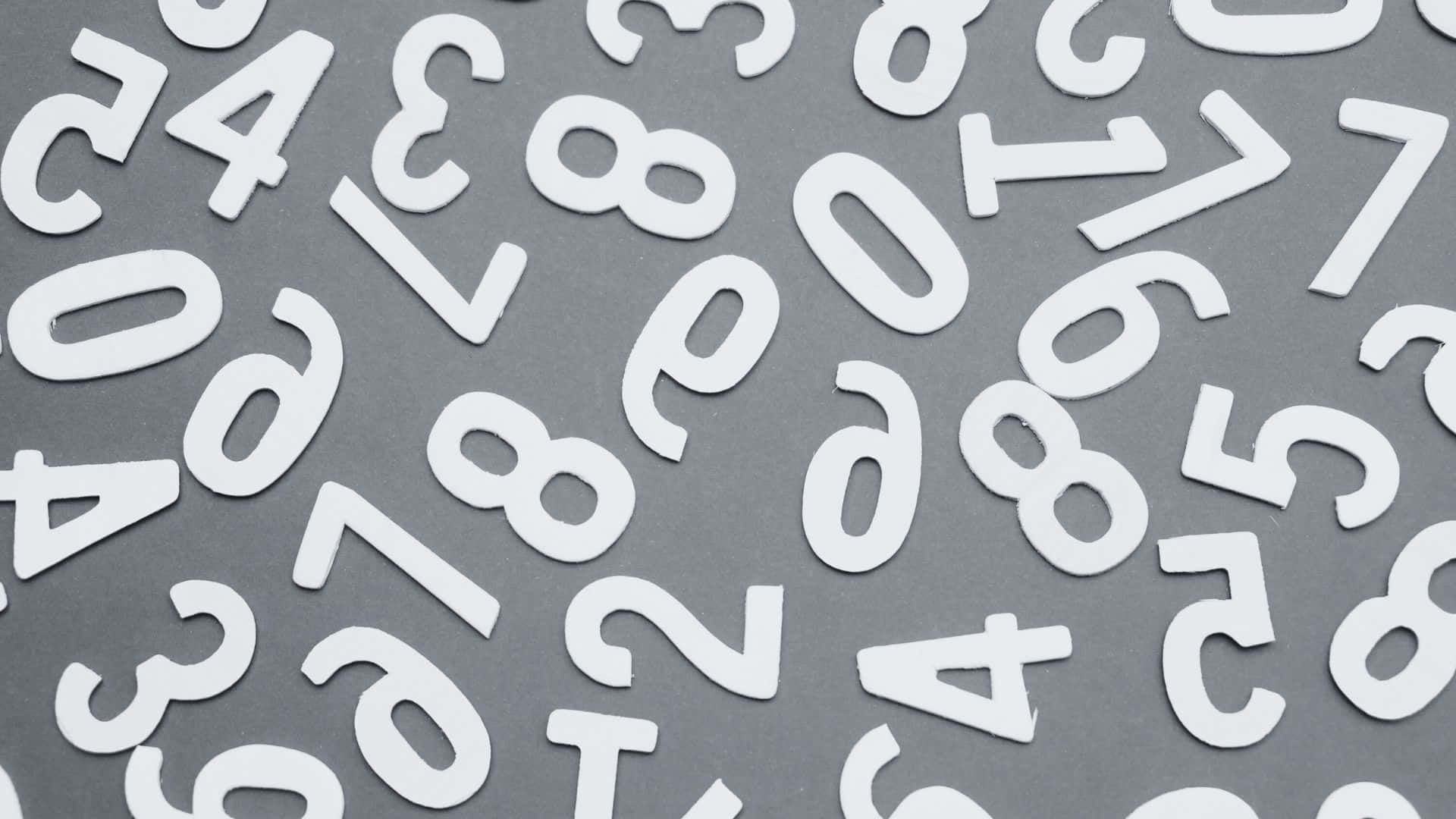 Black And White Number 桌布 壁紙 — 白色鏤空數字雜亂地散落在灰色表面上，形成極簡抽象圖案。