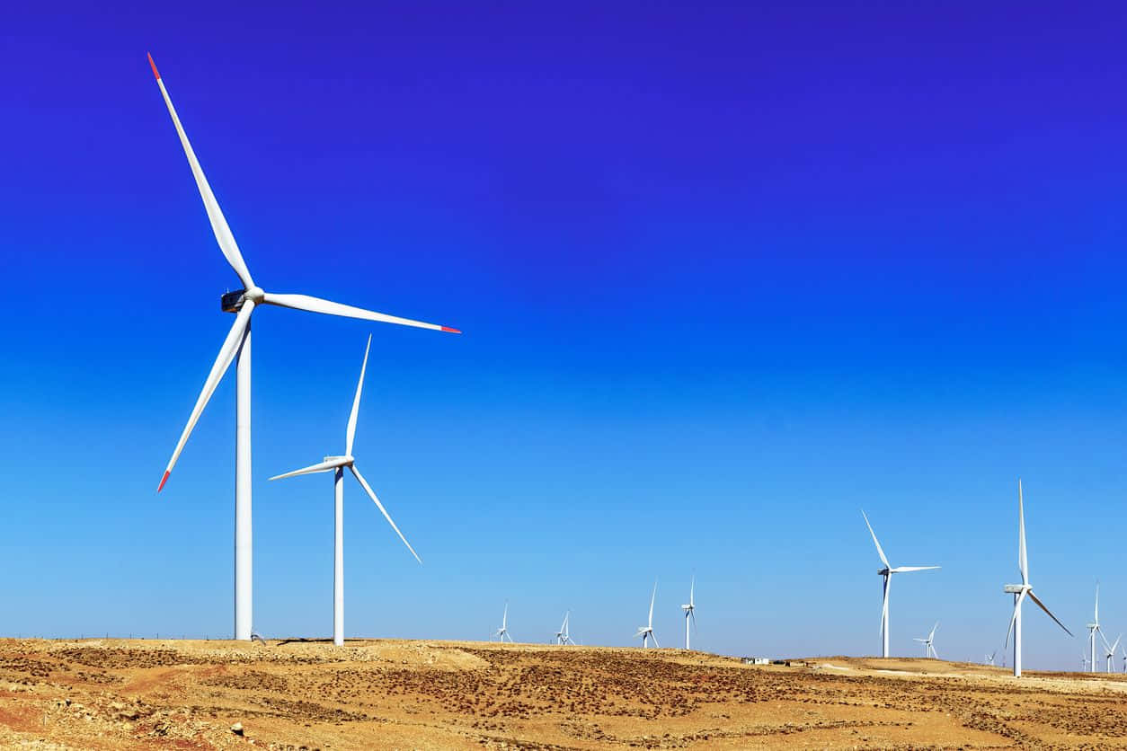 Renewable Energy 桌布 壁紙 — 白色風力渦輪機在乾燥的金色景觀上，襯著鮮豔的藍天高高矗立。
