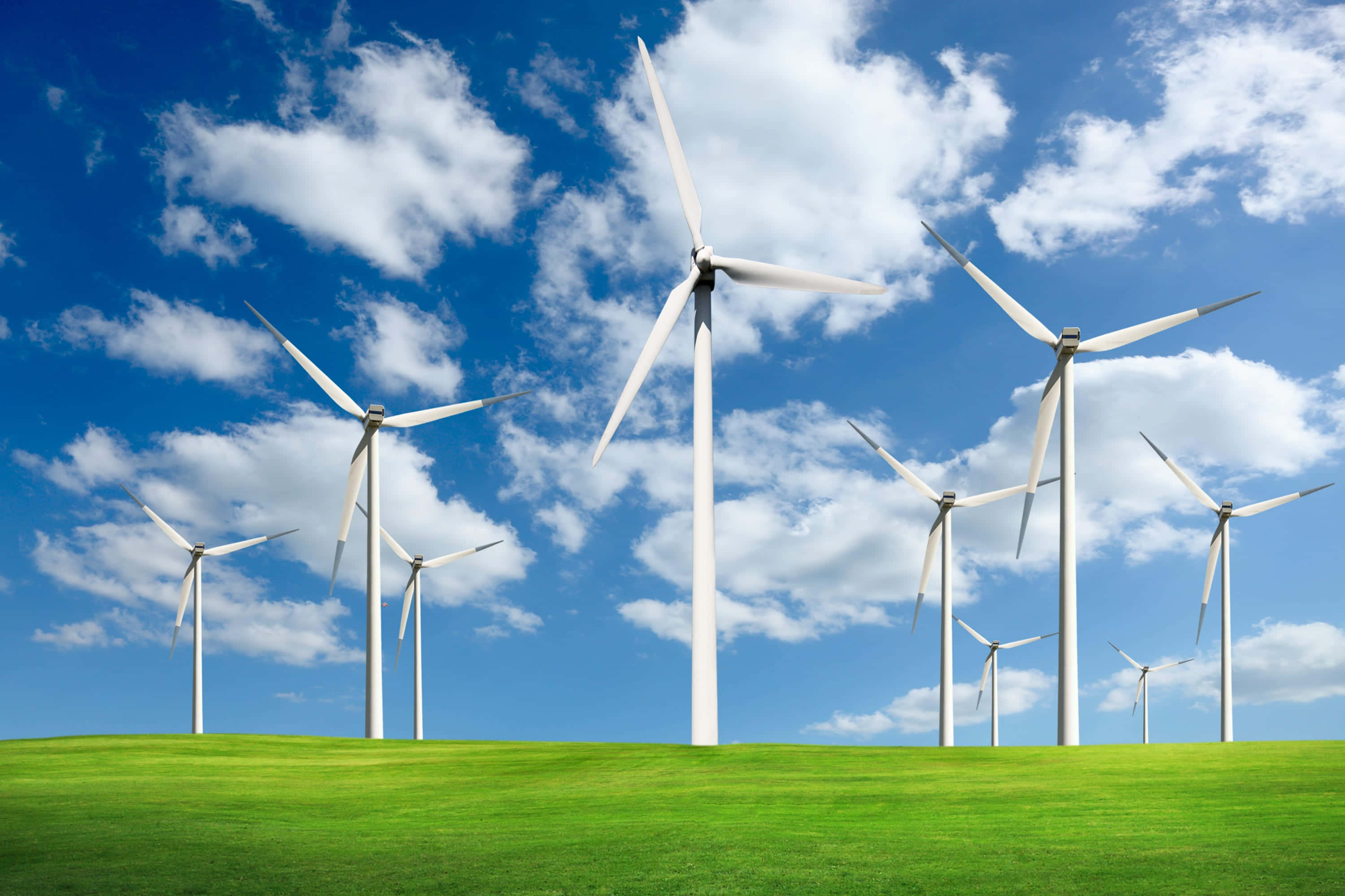 Energy 桌布 壁紙 — 白色風力渦輪機在明亮的藍天下，聳立在充滿活力的綠色山丘上，天空中有蓬鬆的白雲。