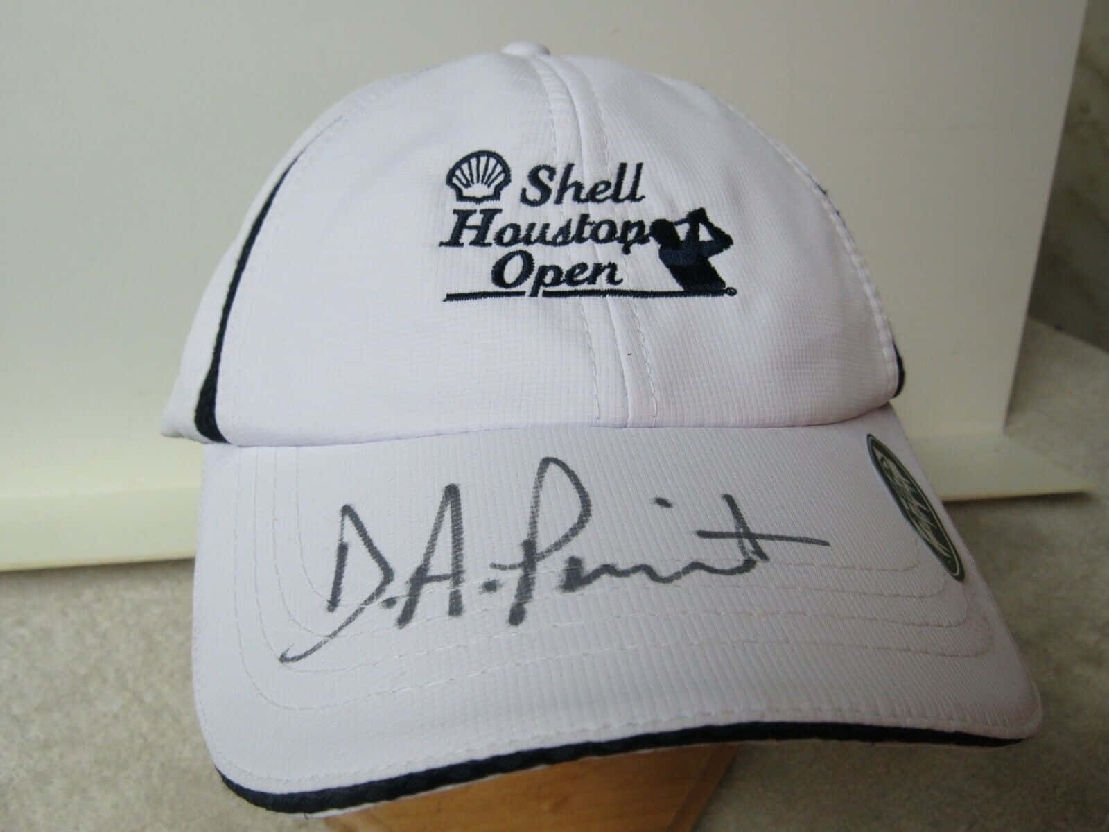 Cap 桌布 壁紙 — 白色高爾夫球帽，帽檐上有Shell Houston Open標誌和D A Pont簽名。