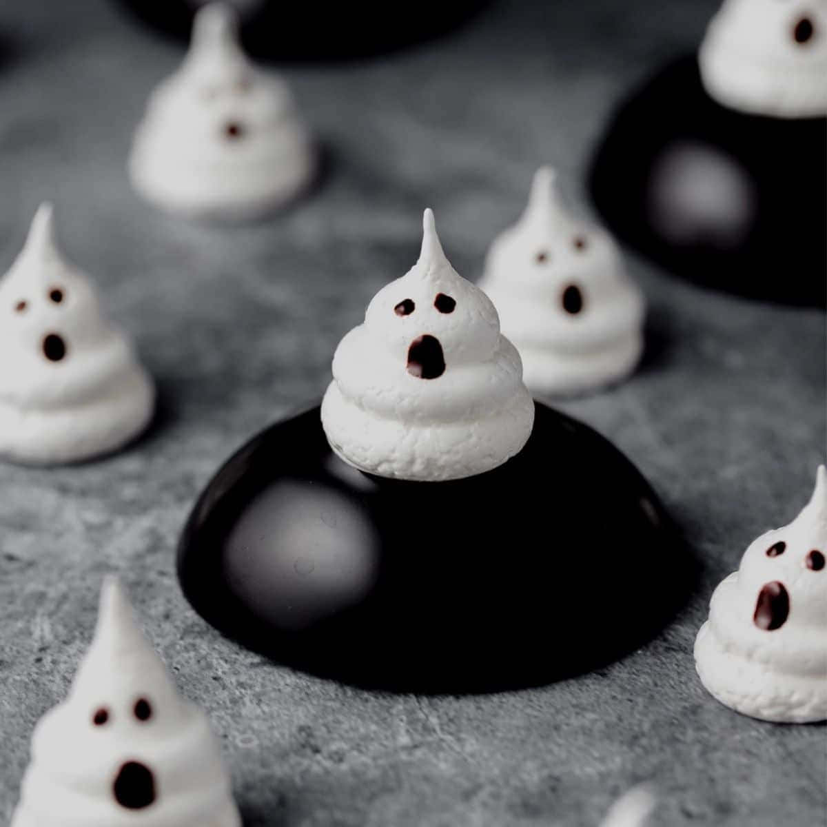 Meringue 桌布 壁紙 — 白色鬼魂形狀的蛋白霜，帶有巧克力眼睛和嘴巴，放在灰色表面上的黑色巧克力圓片上。