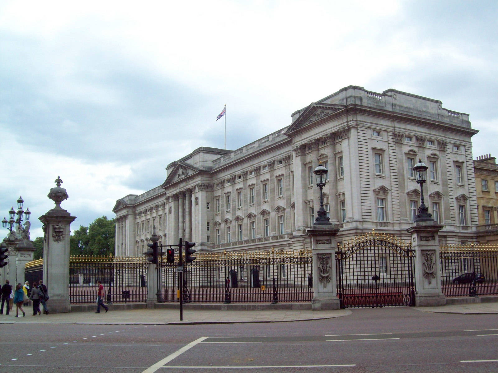 England 桌布 壁紙 — 白金漢宮的白色石砌宏偉外牆矗立在華麗的黑金大門後，天空多雲。