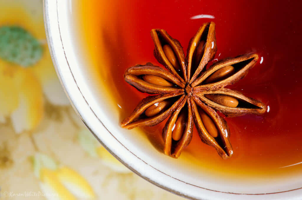 Morning Tea 桌布 壁紙 — 白陶瓷杯內濃郁琥珀色茶中漂浮的八角特寫。