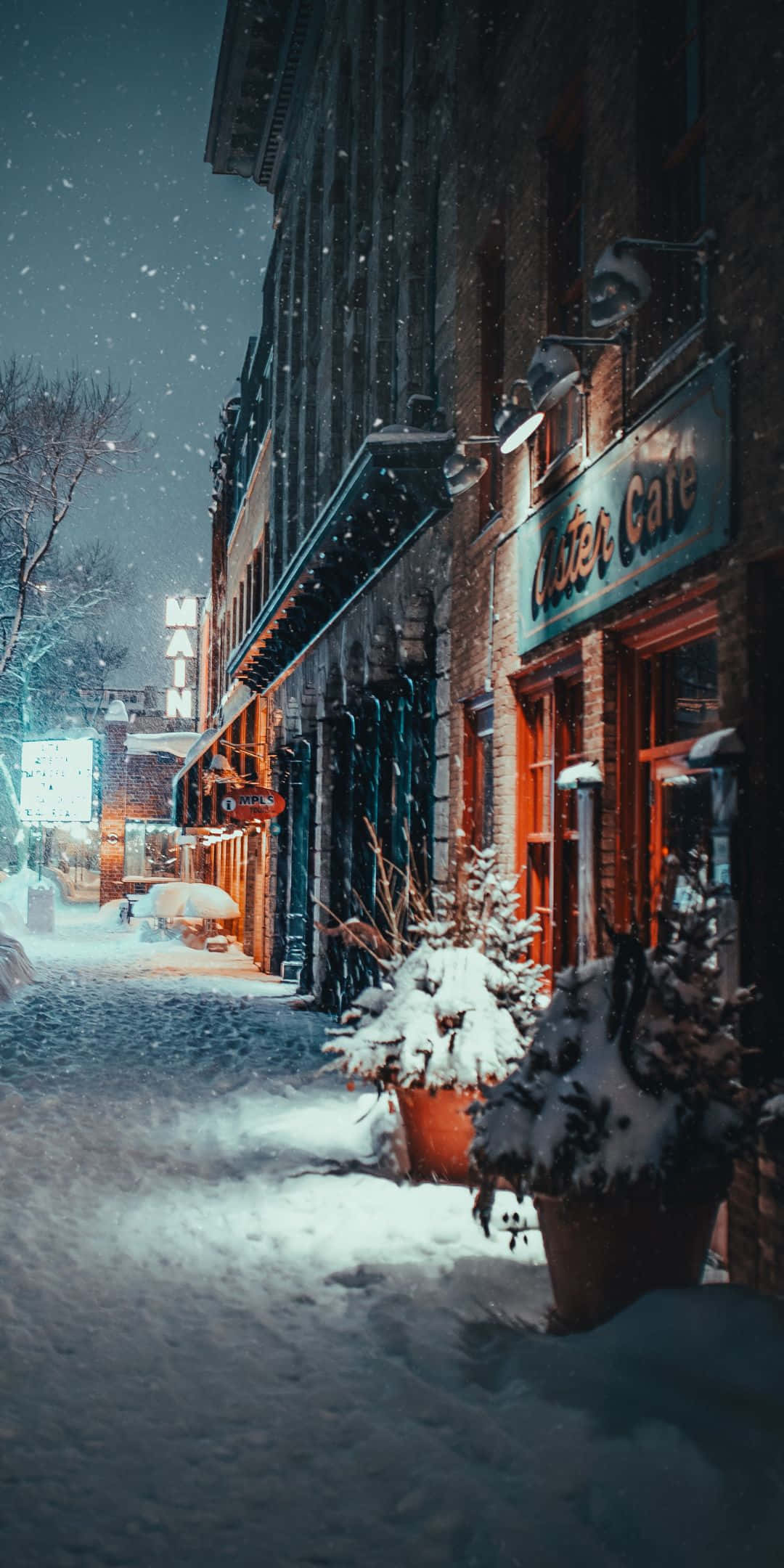 冬天 桌布 壁紙 — 白雪覆蓋寧靜的冬夜街道，溫暖的咖啡館燈光映照在磚砌建築上。